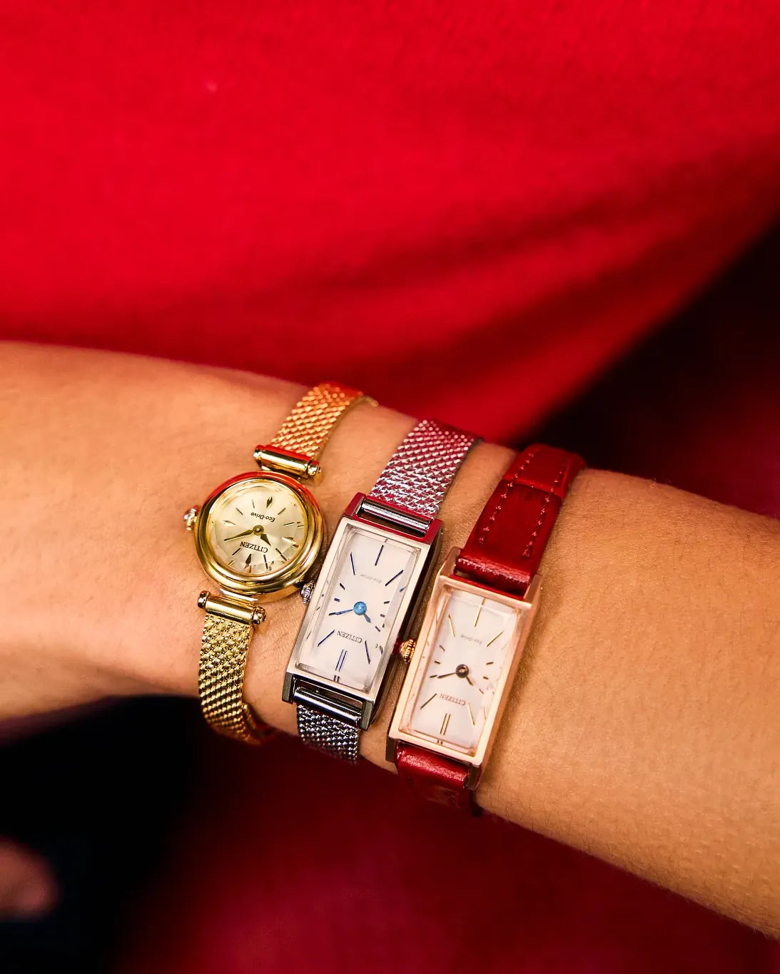 Three watches on a wrist against a red background