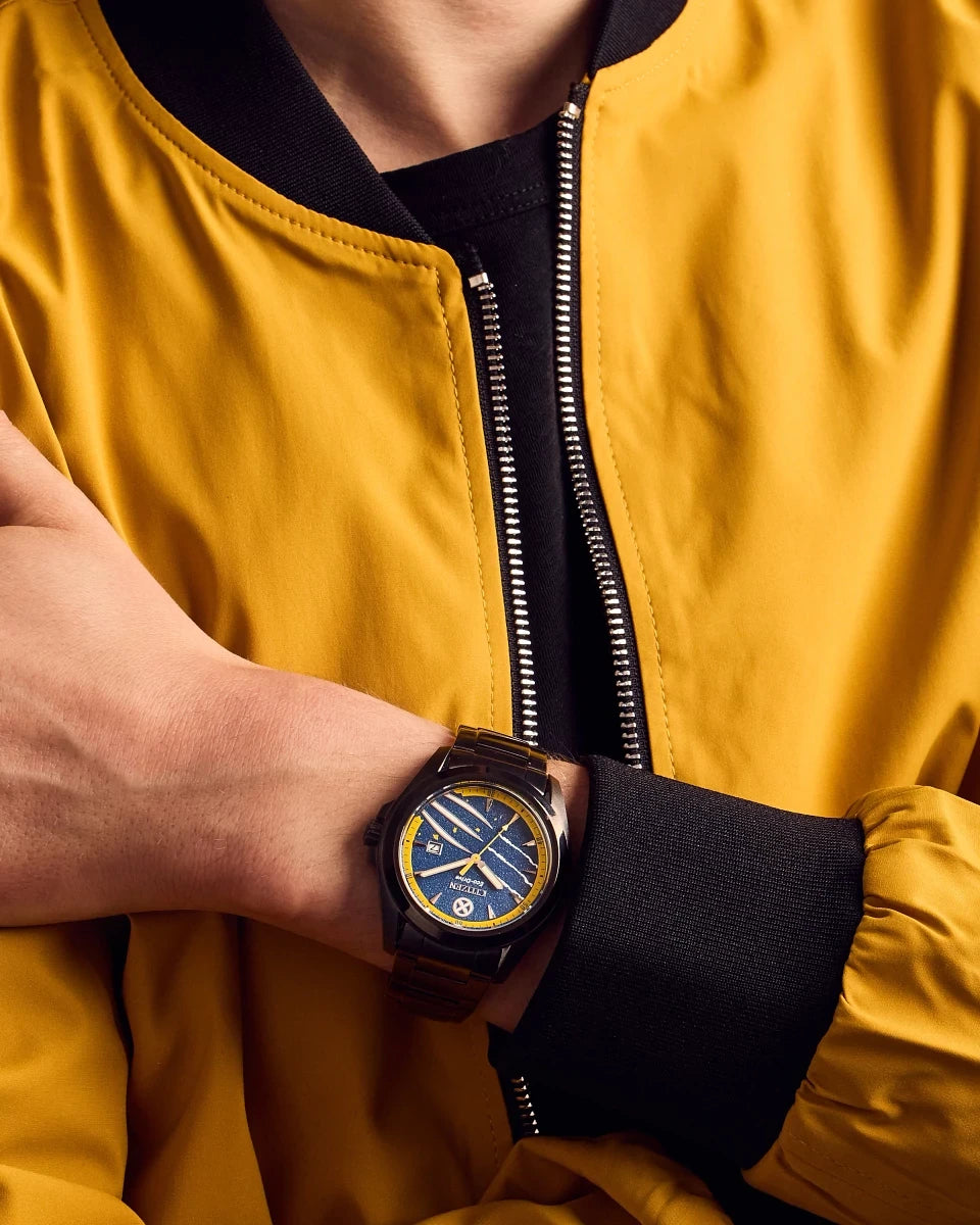 Citizen Marvel Wolverine AW1435-66W worn on wrist with yellow jacket styling, featuring blue dial, yellow outer ring, black stainless steel bracelet, and Wolverine claw motifs