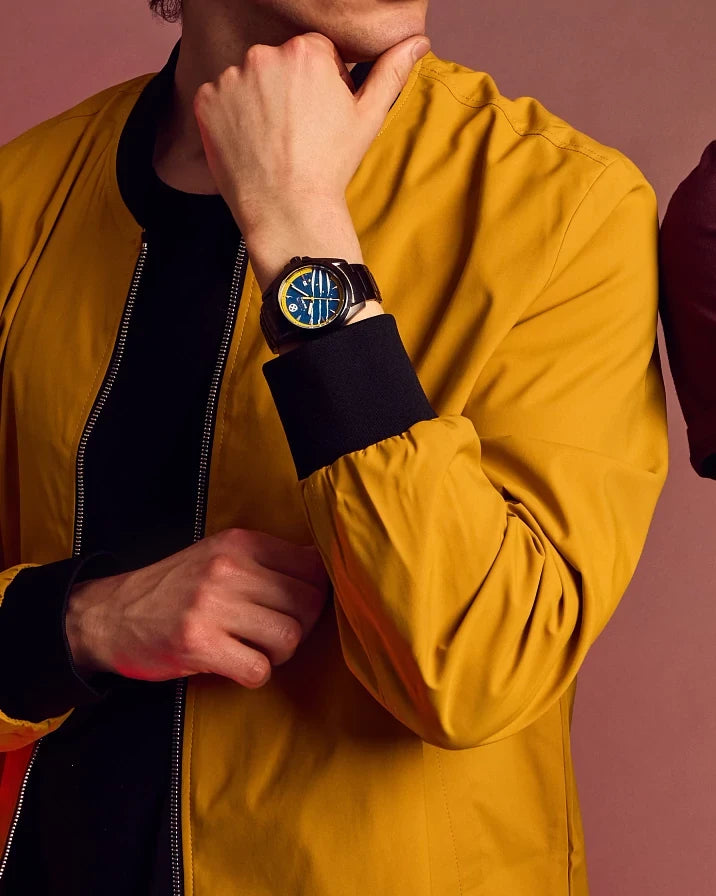 Lifestyle image of the Citizen Marvel Wolverine AW1435-66W Eco-Drive watch worn with a yellow jacket, showing the blue Wolverine-inspired dial and black ion-plated bracelet.