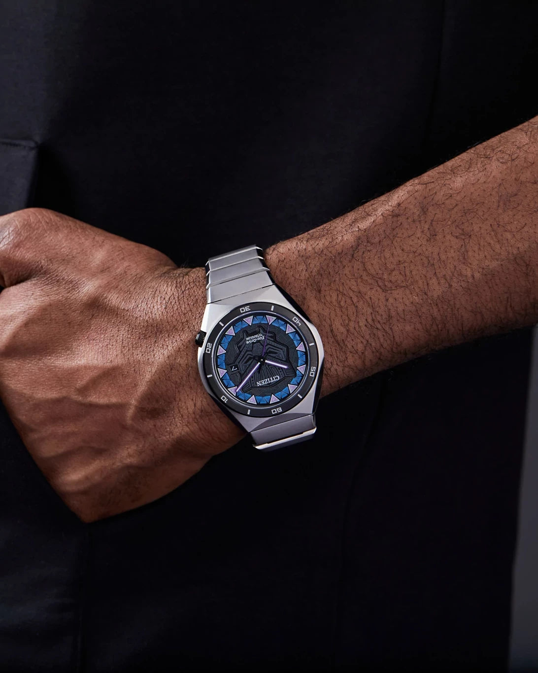 Lifestyle image of the Citizen Black Panther AW1668-50W worn on wrist, featuring the black patterned dial, blue and purple accents, and Super Titanium bracelet.