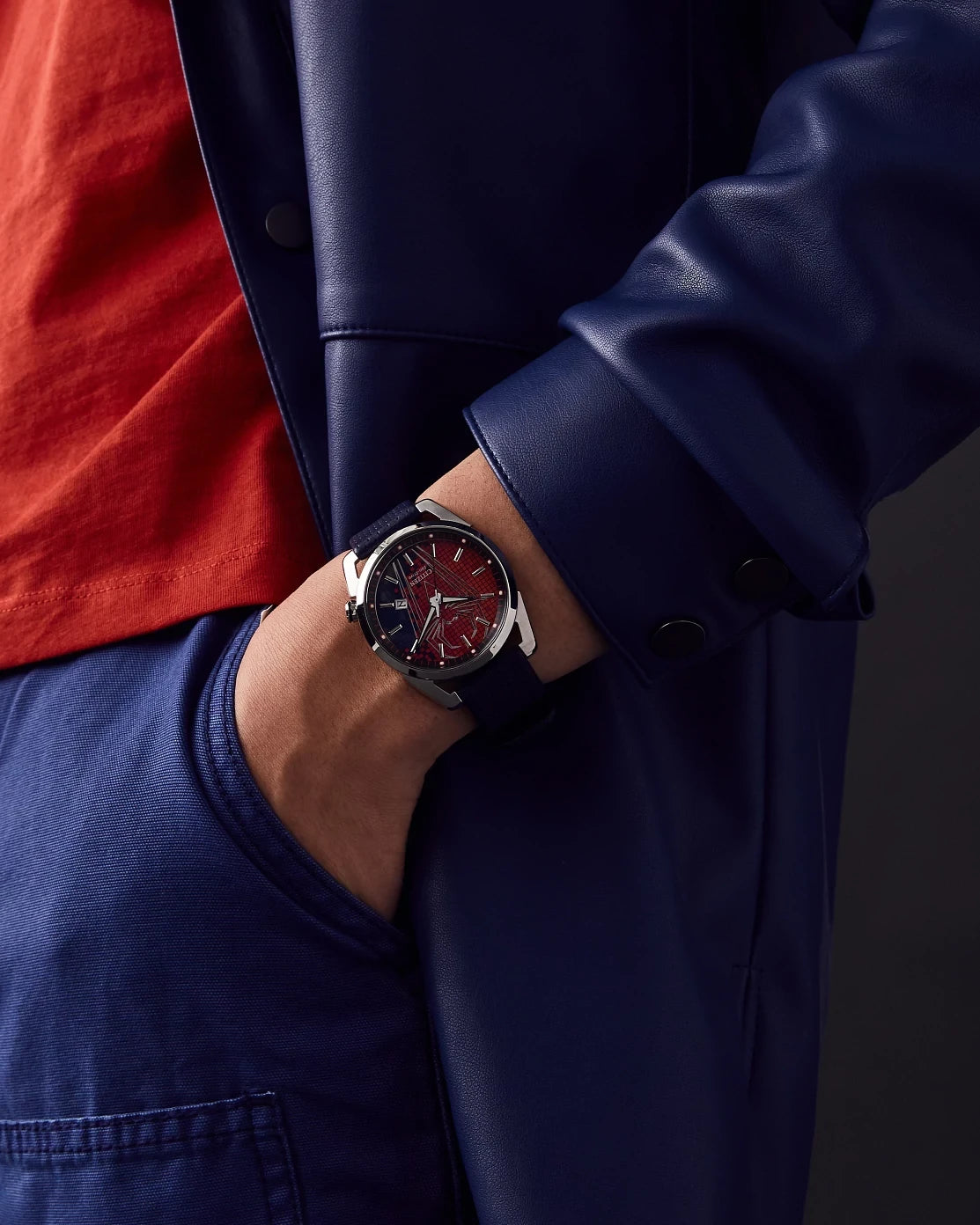 Citizen Spider-Man AW1680-03W worn on wrist with blue jacket styling, featuring the red Spider-Man-inspired dial, silver-tone case, and blue perforated leather strap