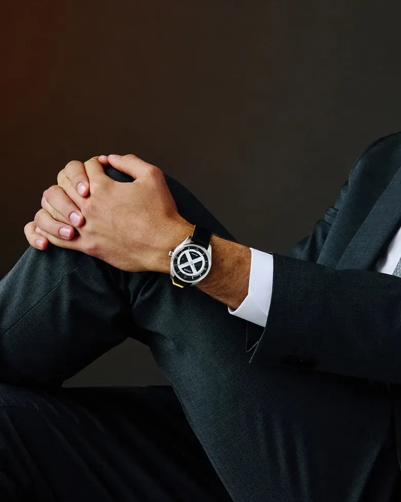 Citizen Marvel X-Men AW5007-17W Eco-Drive watch worn with a dark suit, featuring a silver X-Men dial design, black leather strap with yellow edging, and silver-tone stainless steel case.
