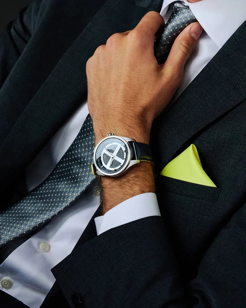 Close-up lifestyle image of the Citizen Marvel X-Men AW5007-17W Eco-Drive watch on wrist with dark suit styling, silver X-Men dial motif, black leather strap, and yellow accent detail.