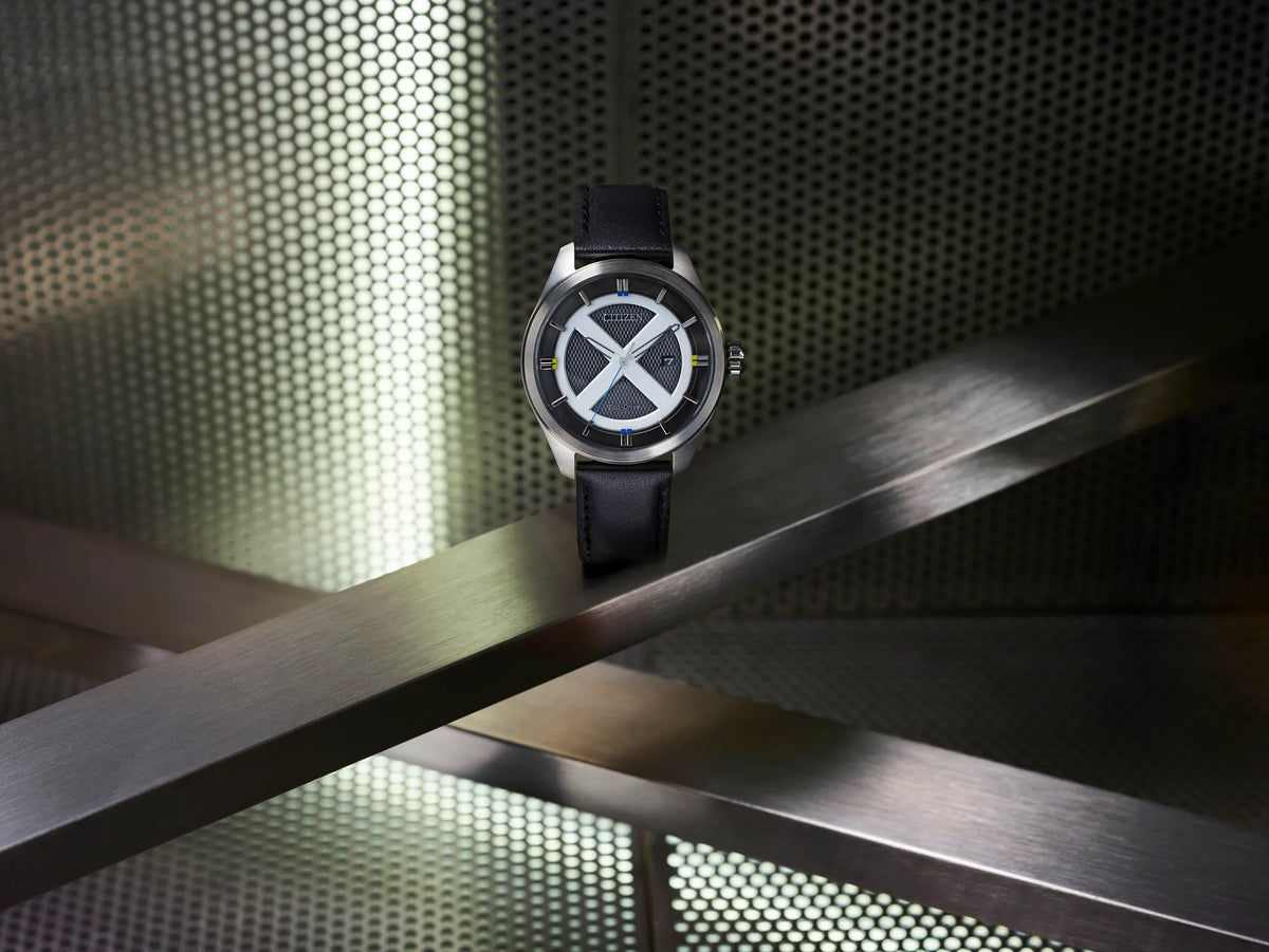 Citizen Marvel X-Men AW5007-17W Eco-Drive watch displayed on an industrial metal background, featuring a silver X-Men logo dial, black leather strap, and silver-tone stainless steel case.