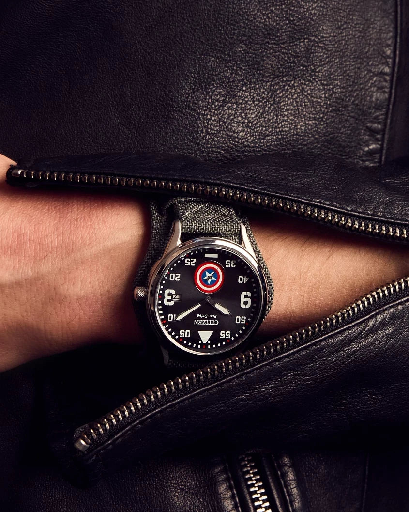 Lifestyle image of the Citizen Captain America Forever BV1140-00W worn under a black leather jacket, featuring the shield sub-dial and dark gray cuff strap