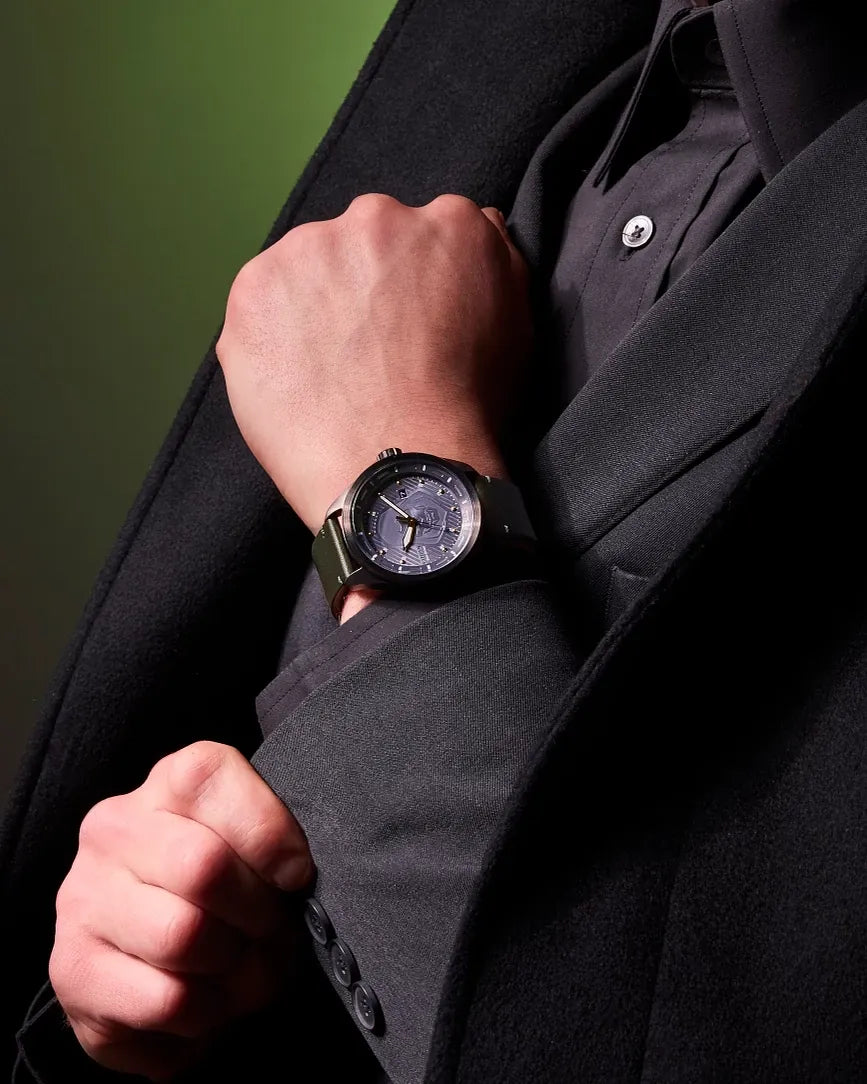Citizen Avengers Dr. Doom AW5027-44W Eco-Drive watch worn on the wrist with green leather strap, gray dial, and black case.