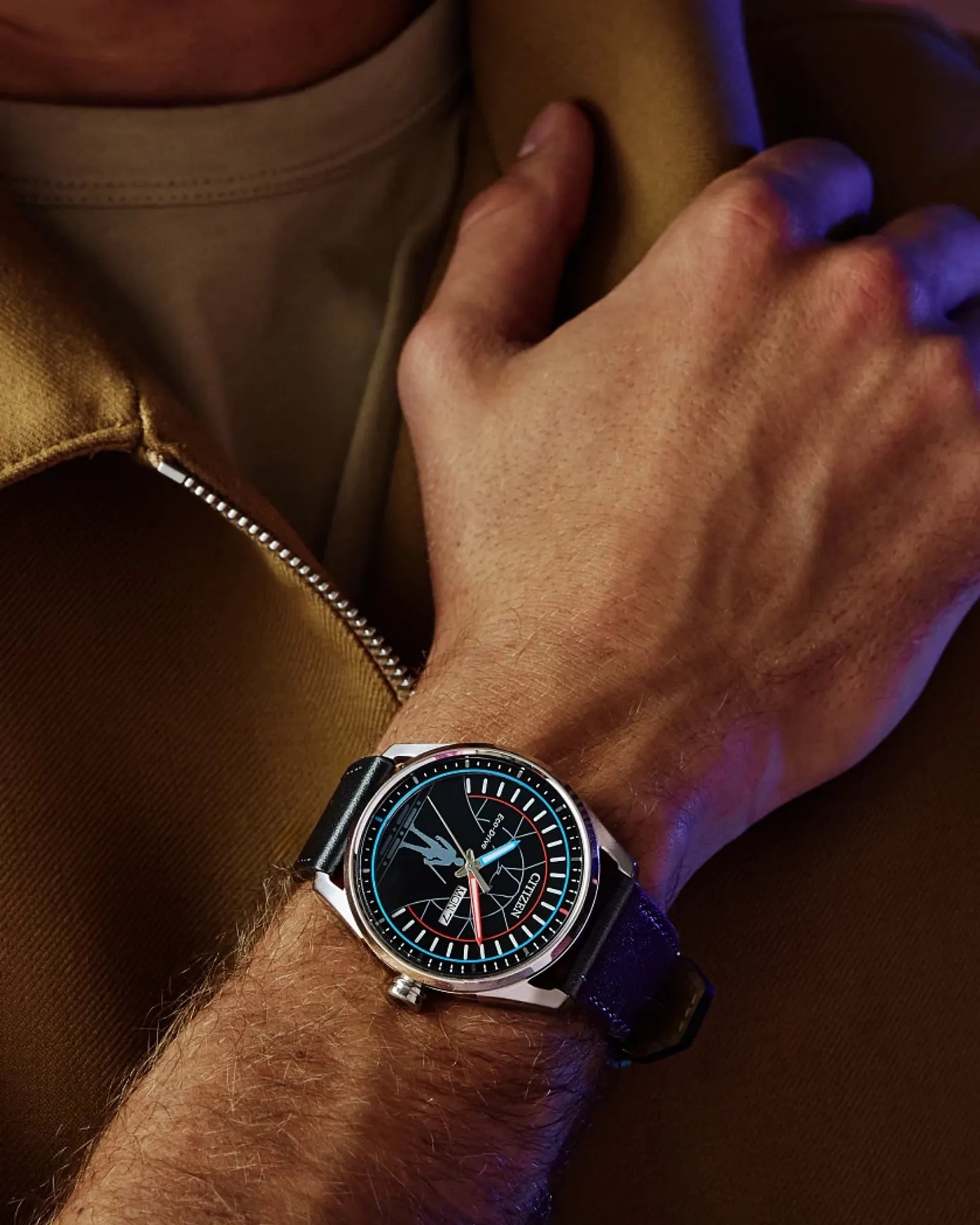 Close-up of a wrist wearing a watch with a brown leather jacket.