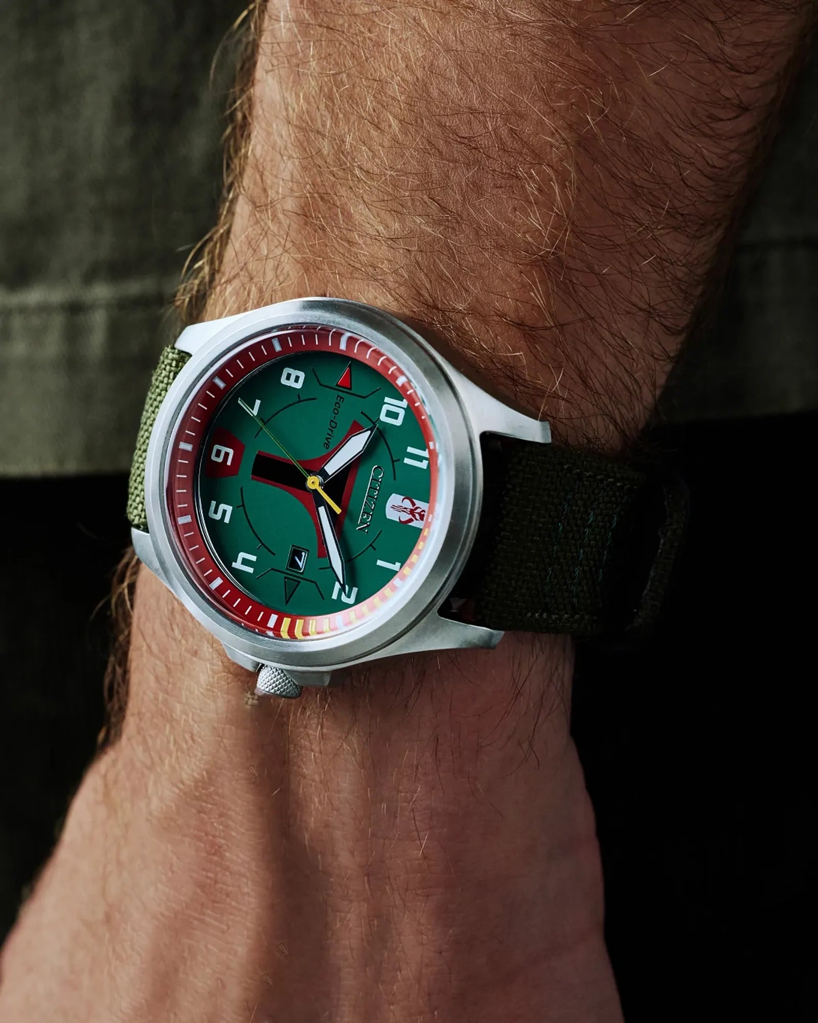 Watch with a green face and red accents on a wrist against a dark background