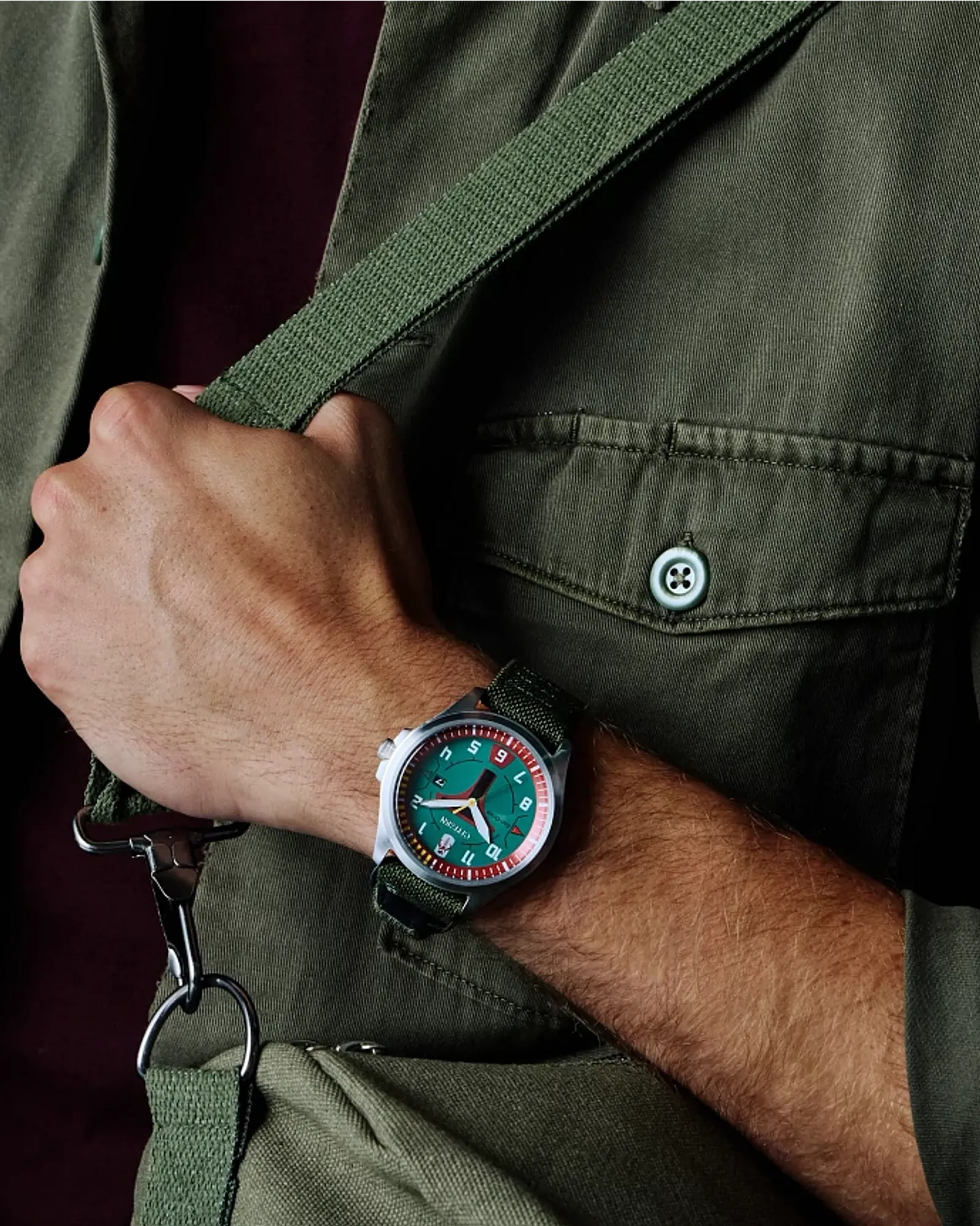 Person wearing a watch with a green face and black strap, holding a green bag.