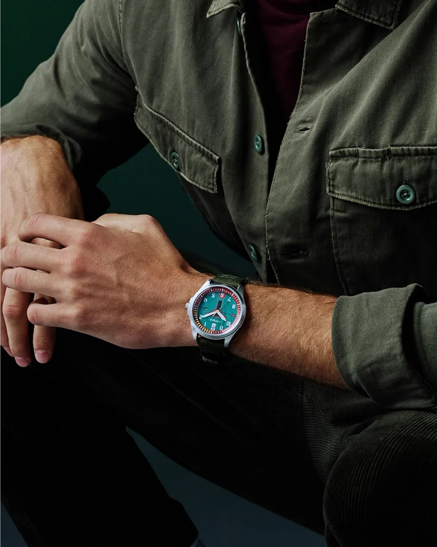 Person wearing a watch with a greenish face on a dark background