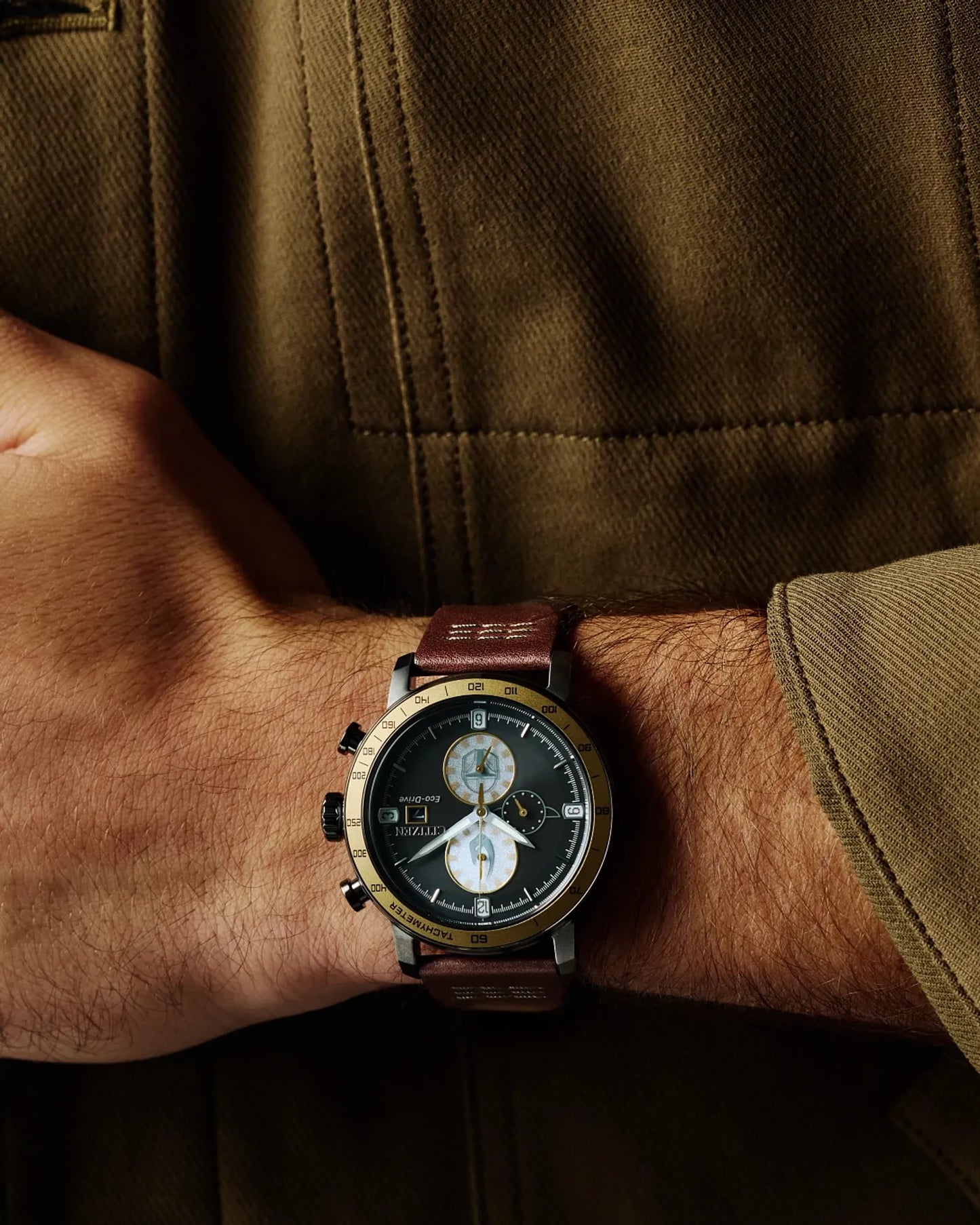 Close-up of a wrist wearing a watch with a brown leather strap against a dark background