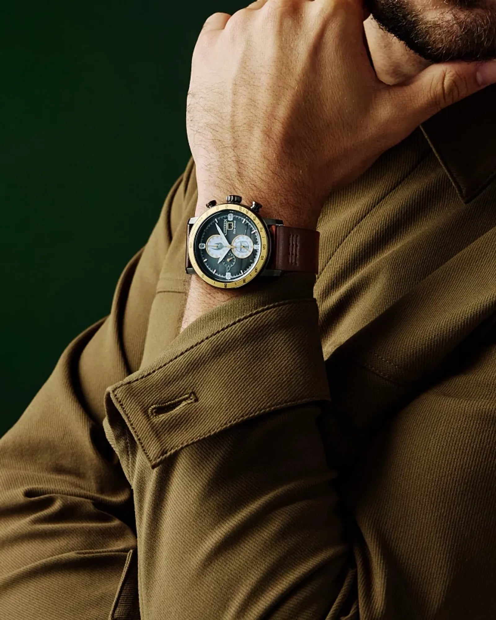 Man wearing a watch with a green background