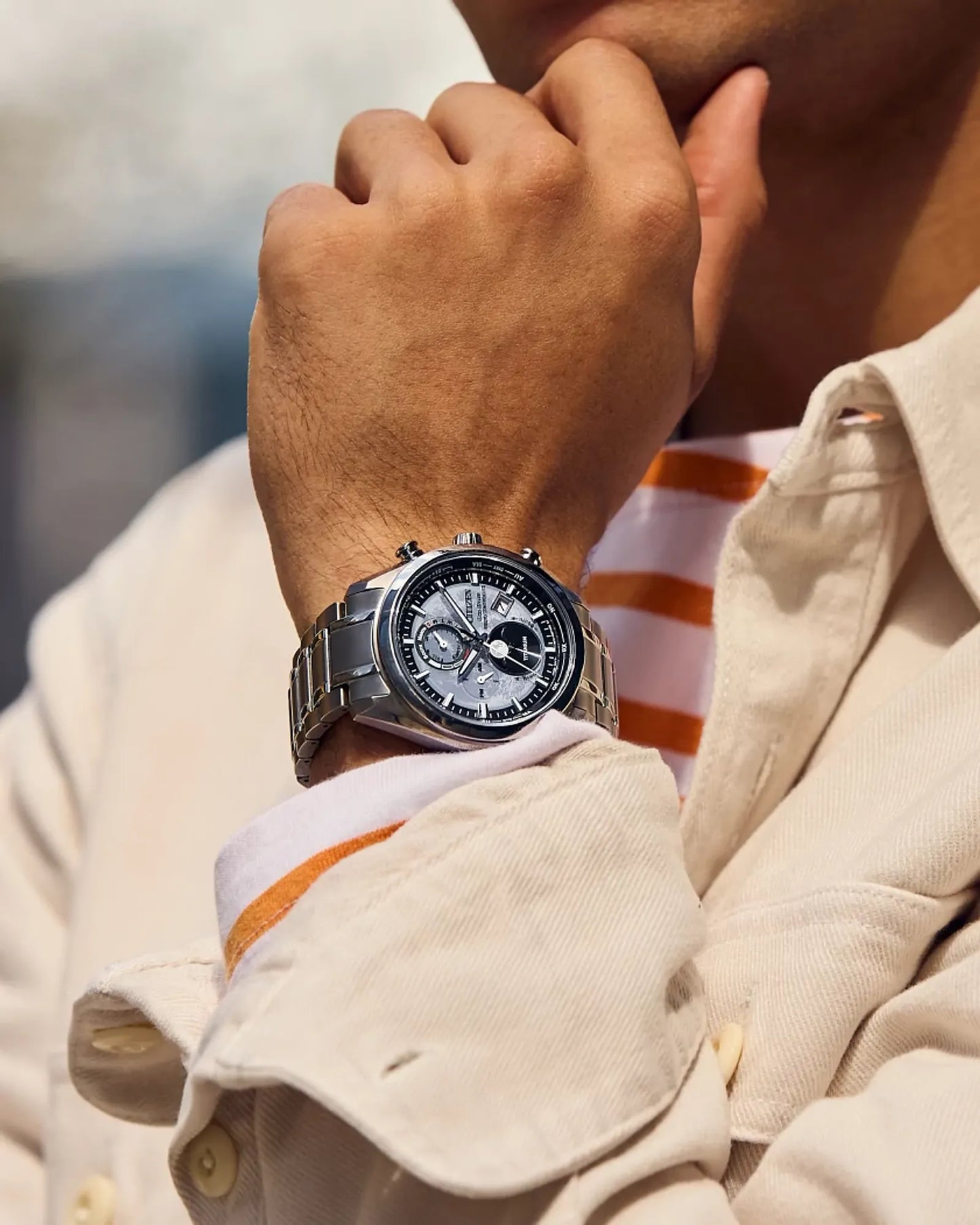 Close-up of a person wearing a silver watch on a blurred background