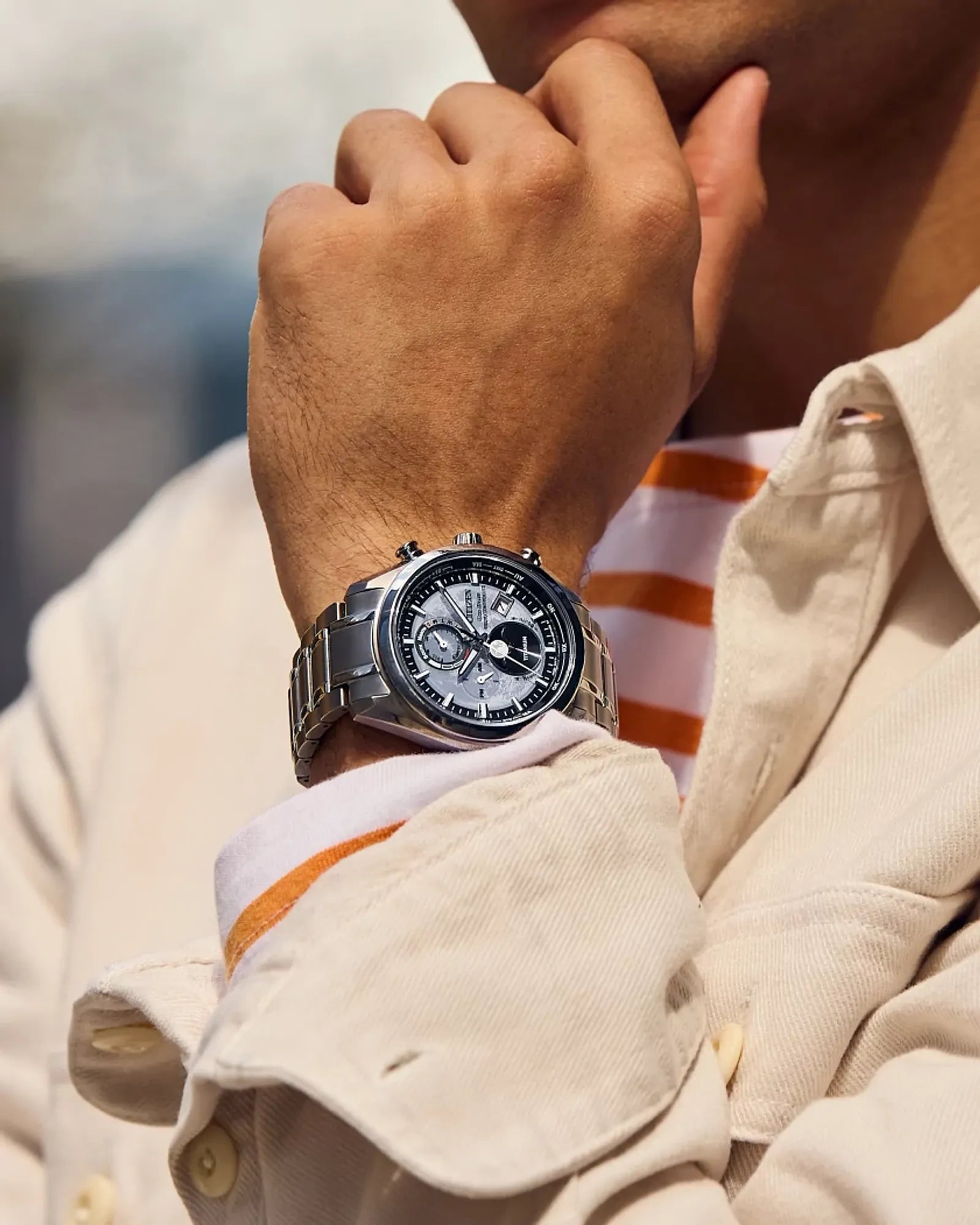 Close-up of a person wearing a silver watch on a blurred background
