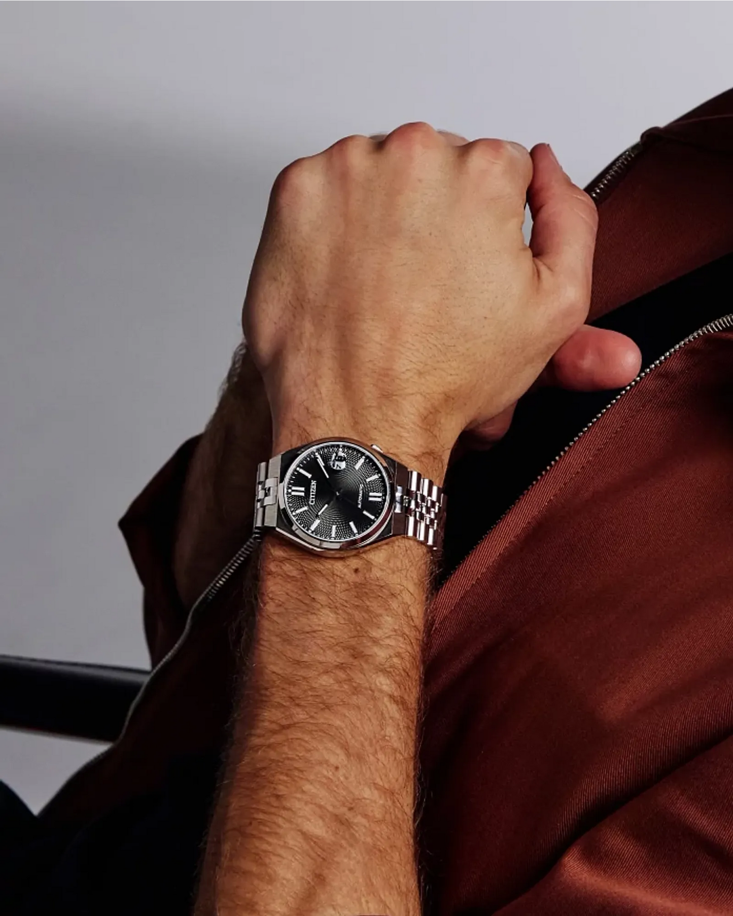Hand wearing a watch with a blurred background