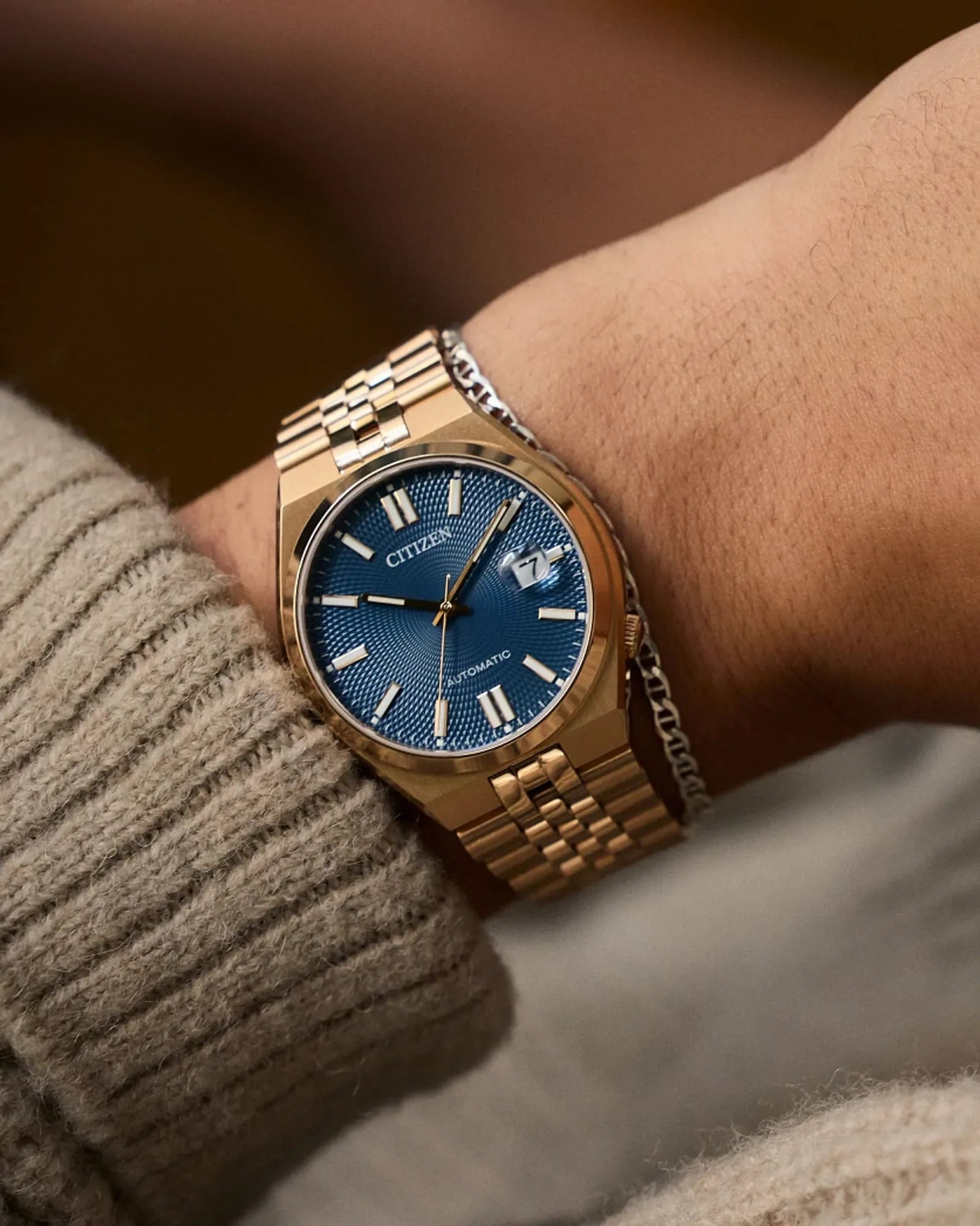 Gold wristwatch with blue dial on a wrist, blurred background