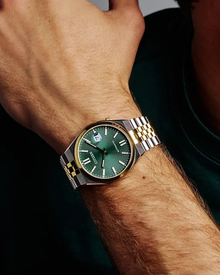 Close-up of a wrist wearing a watch with a green face and gold accents.