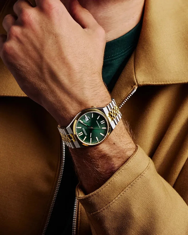 Green watch on a person's wrist with a brown jacket