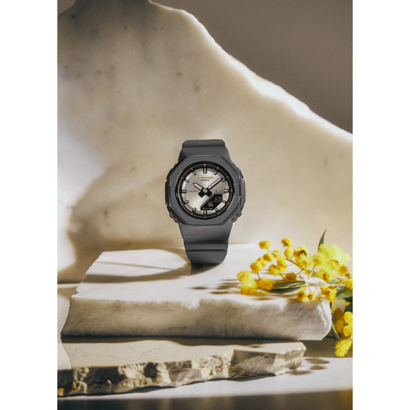 Gray watch on a stack of books with yellow flowers and marble background