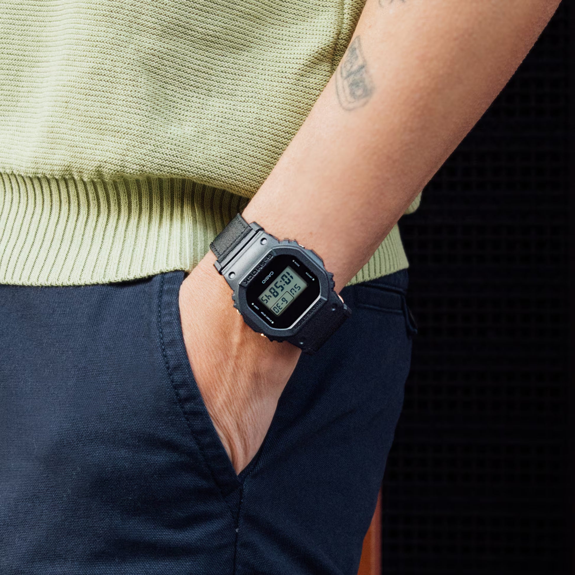 Person wearing a black digital watch on a plain background