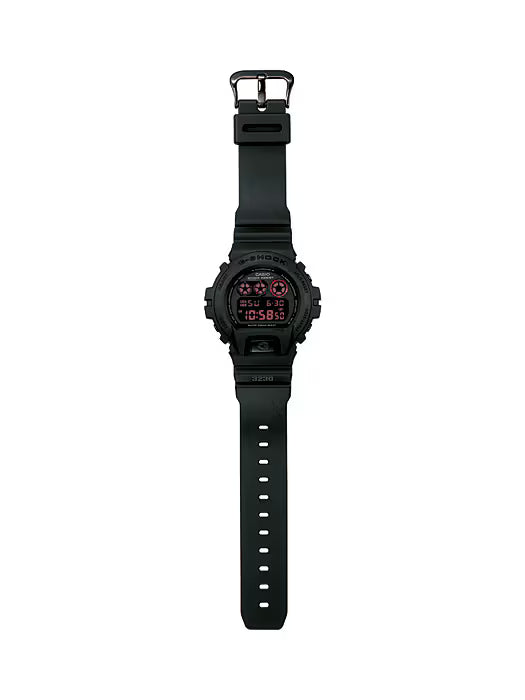 Casio G-SHOCK DW6900MS-1 digital watch in stealth matte black resin case and band with red accents and black ion-plated buttons. Features shock resistance, mineral glass, 200-meter water resistance, electro-luminescent blue-green backlight with afterglow, stopwatch, countdown timer, multi-function alarm, hourly time signal, flash alert, full auto-calendar, and 12/24-hour format. Case size 53.2 × 50 × 18.7 mm, weight 67 g, powered by CR2016 battery with approx. 2-year life.”