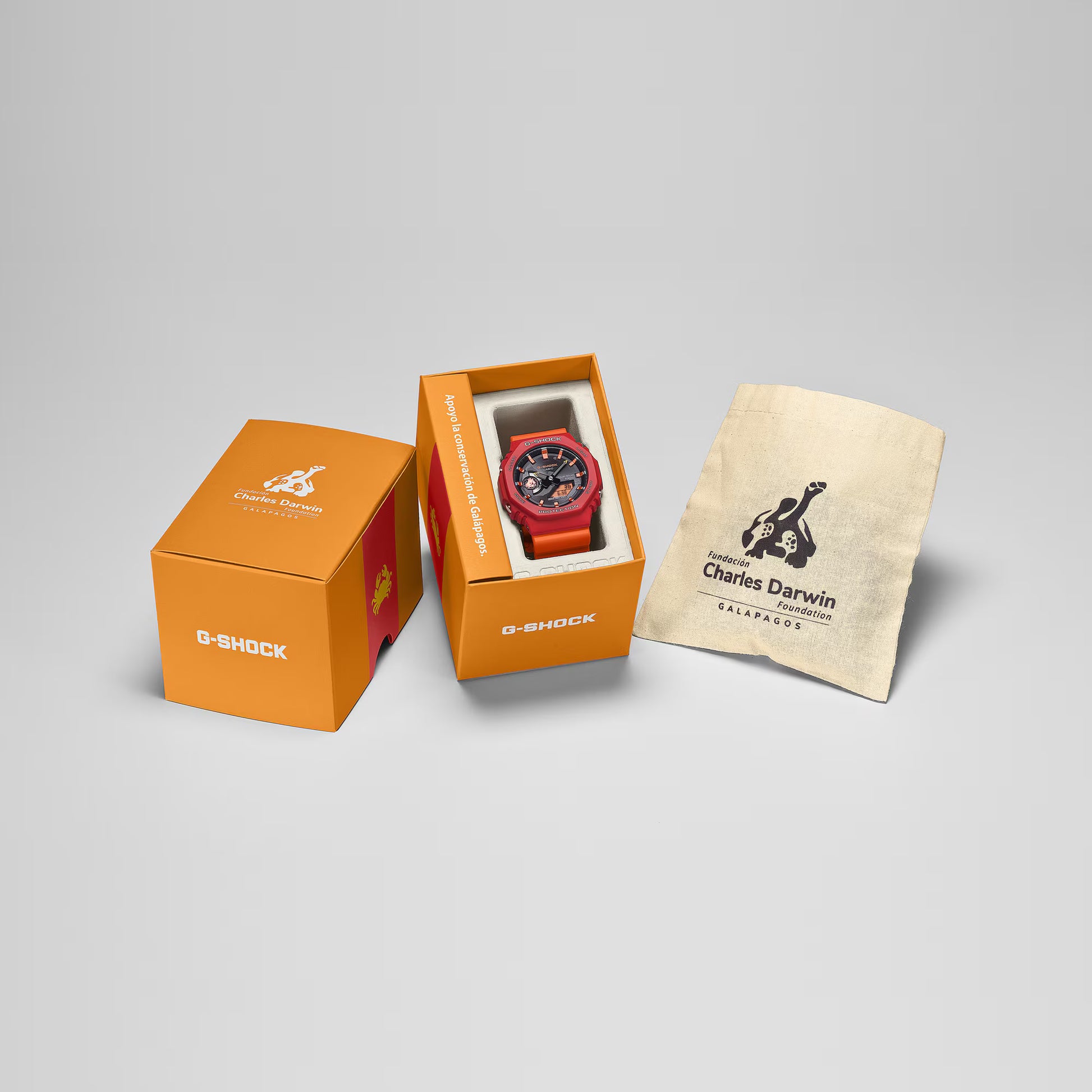 G-Shock watch in an open orange box with a branded cloth on a gray background