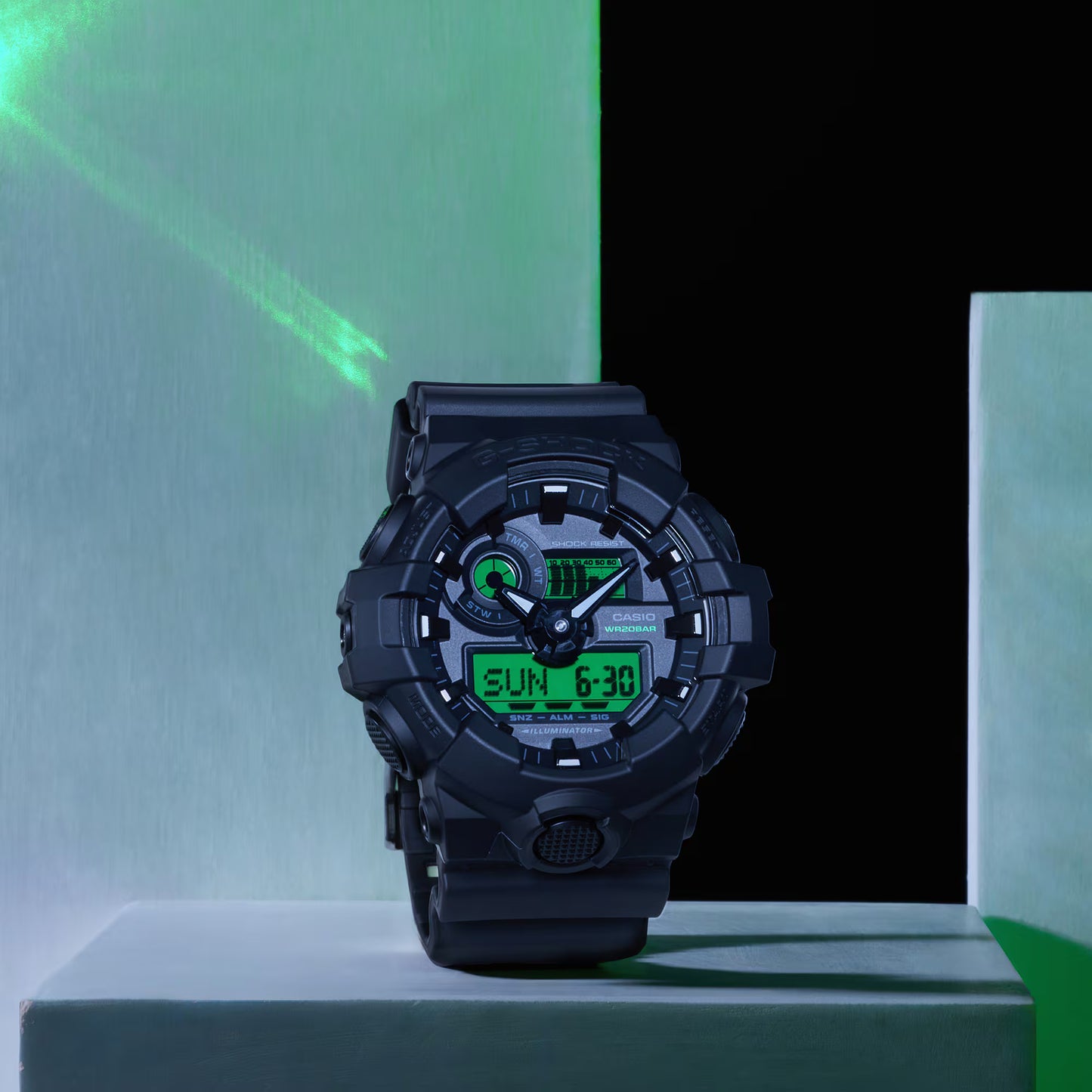 Black digital watch on a green and black geometric background