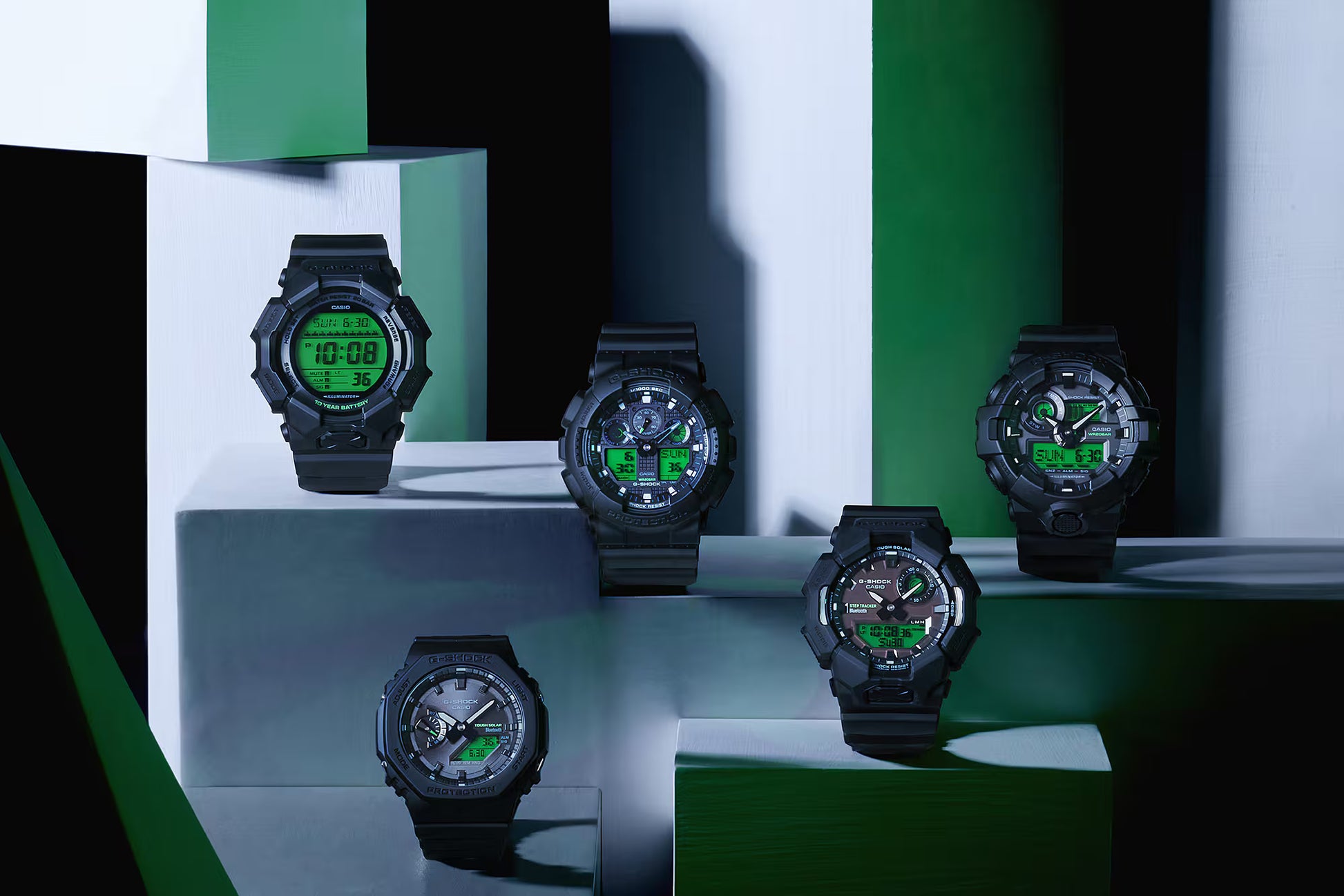 Collection of black digital watches with green displays on a reflective surface.