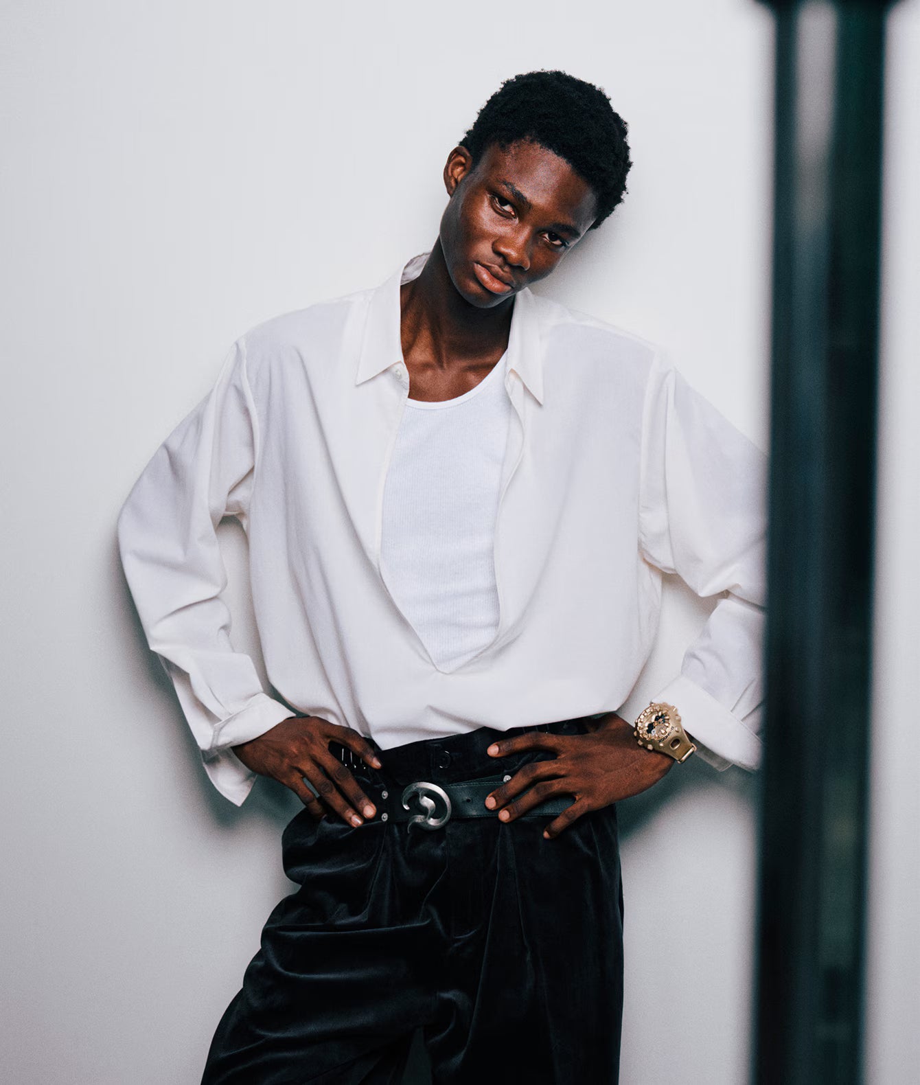 Person wearing a white shirt and black pants against a plain background