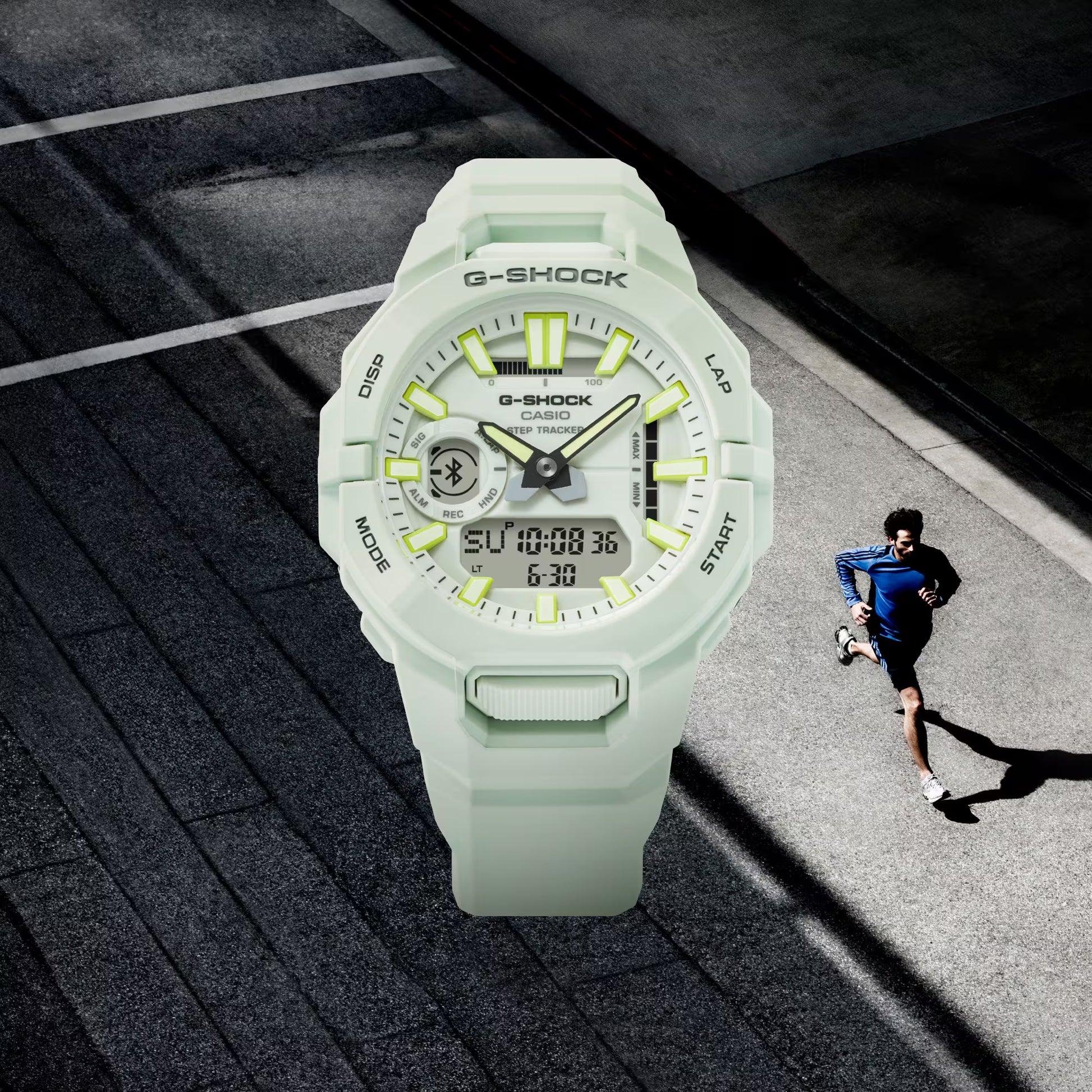 G-Shock watch with a person running in the background on a road.