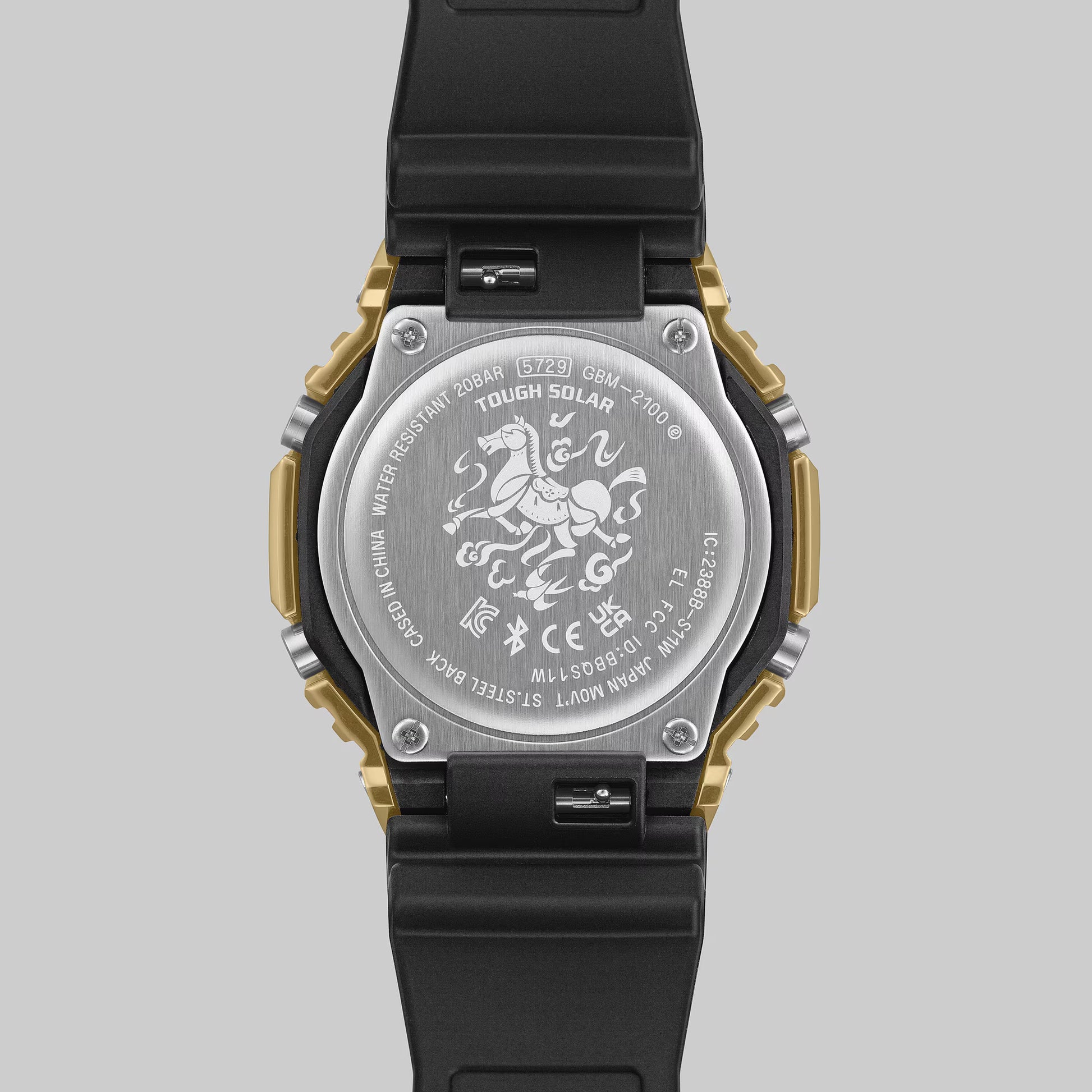 Back view of a watch with engraved design on a gray background