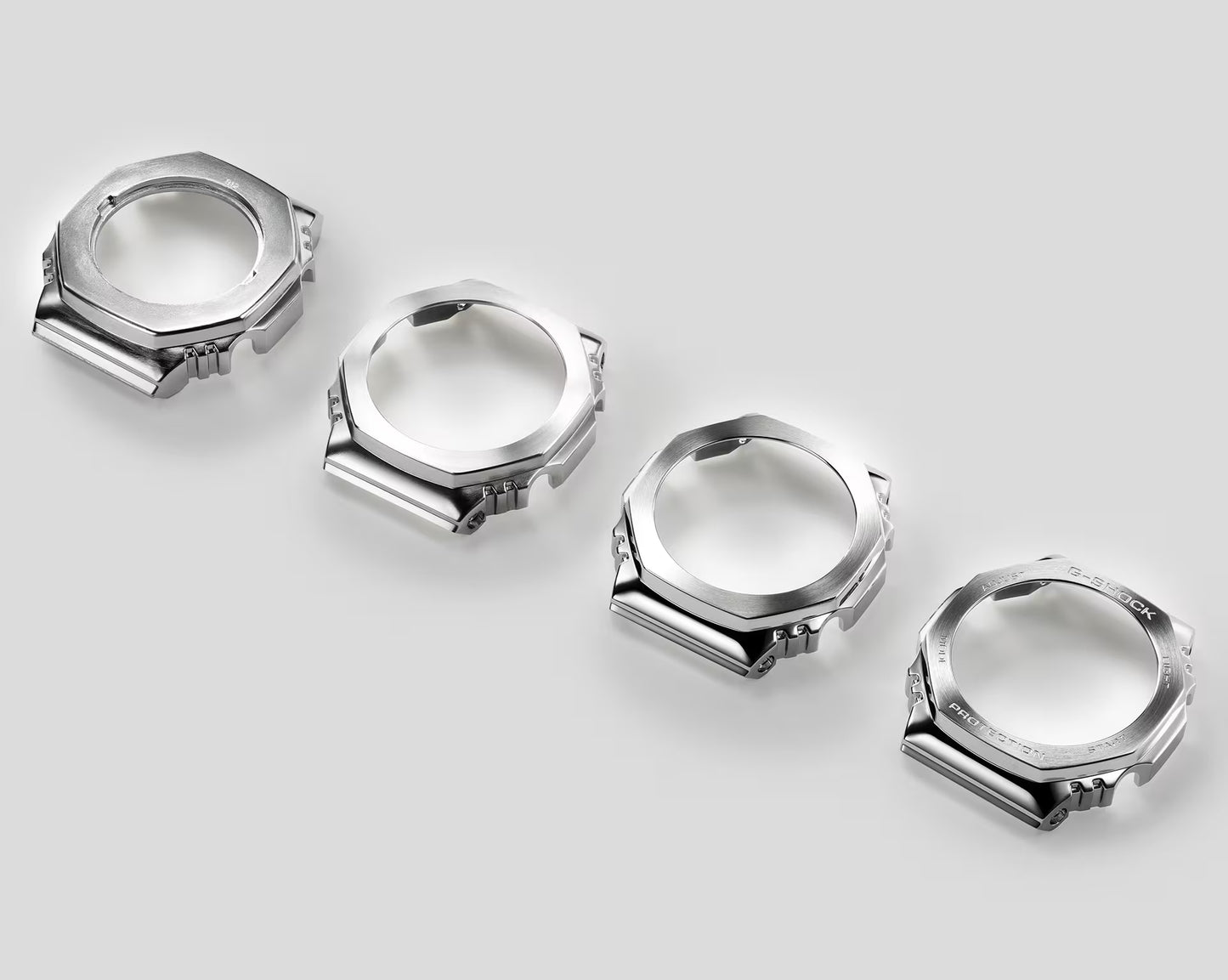 Five silver watch case components on a light gray background