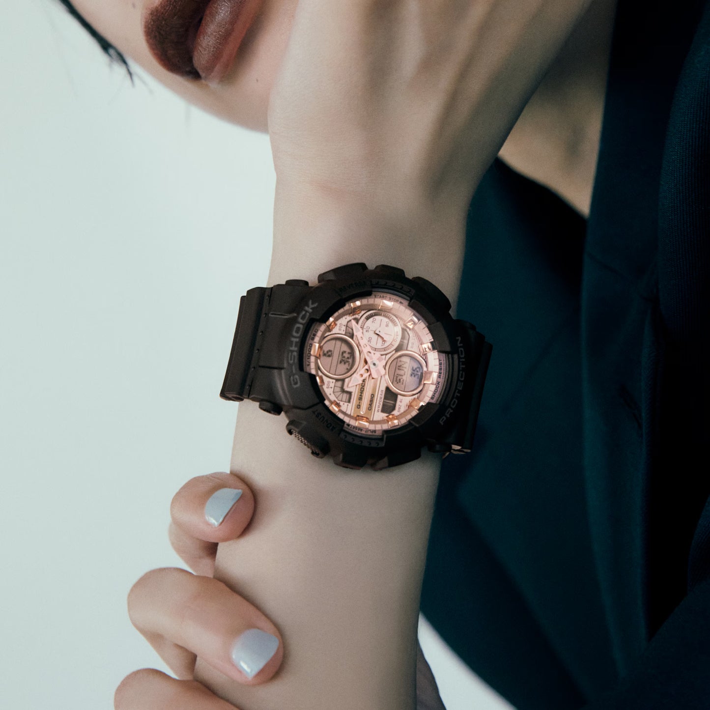 Close-up of a wrist wearing a black and rose gold watch.