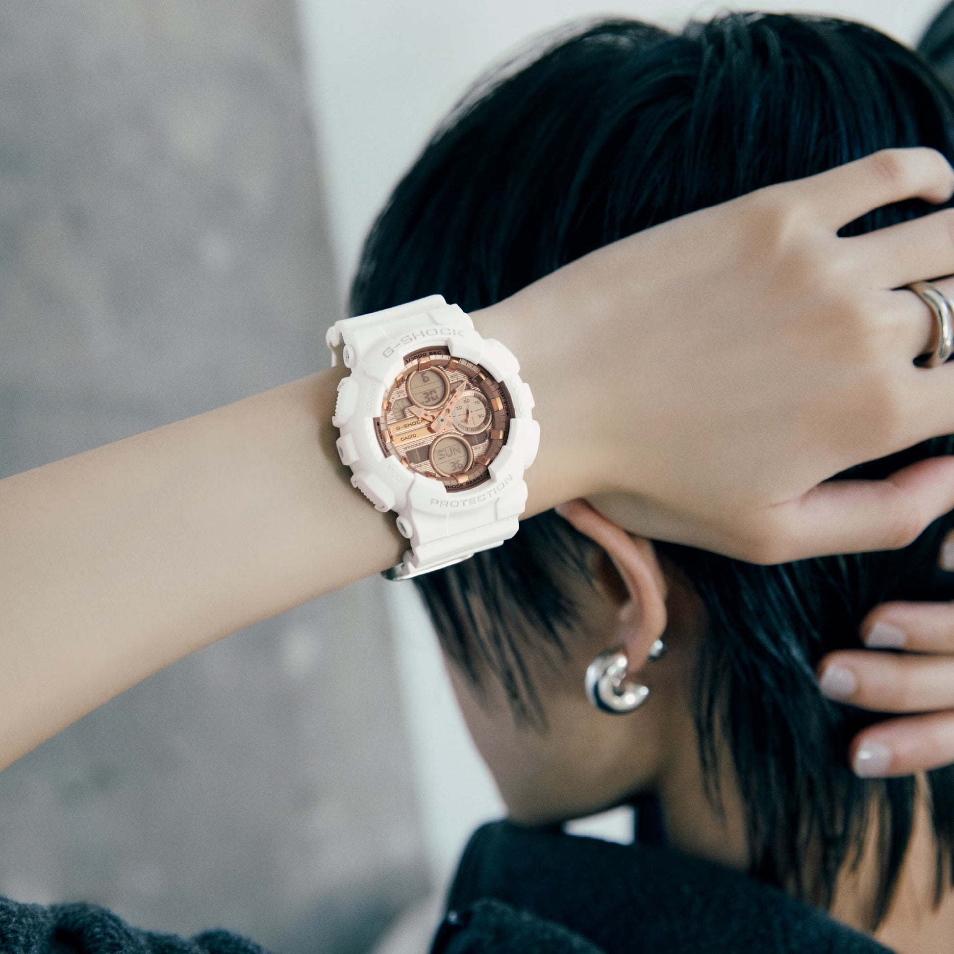 Person wearing a white watch with a brown face, blurred background