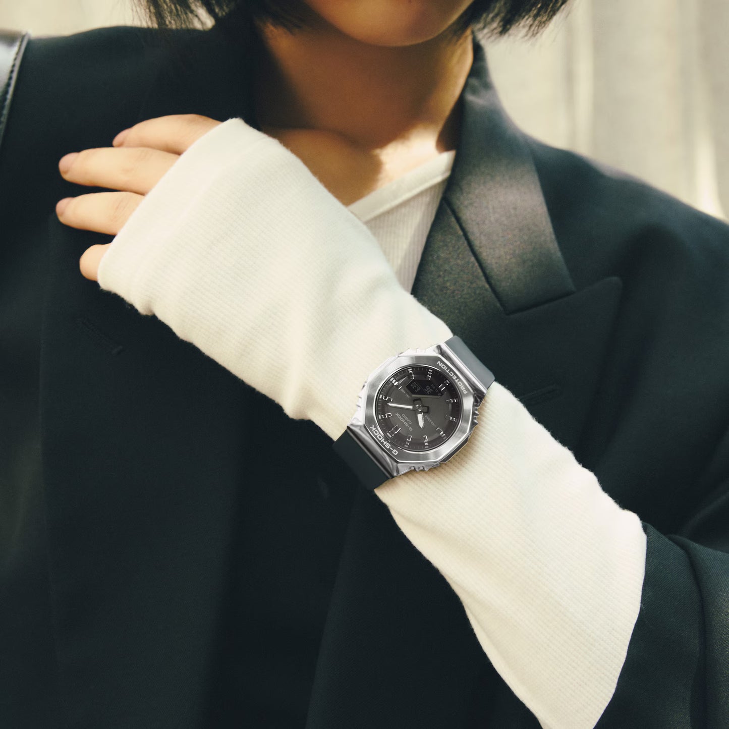 Person wearing a black suit with a silver watch on a blurred background