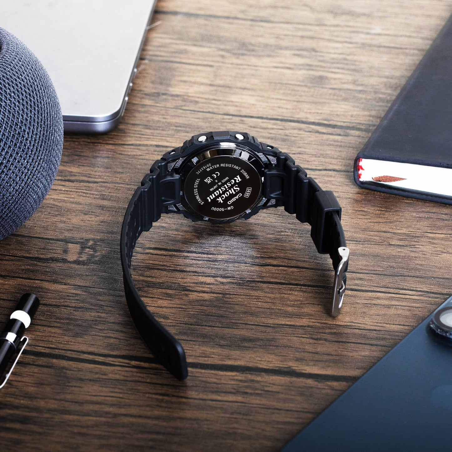 Black wristwatch on a wooden surface with a blurred background