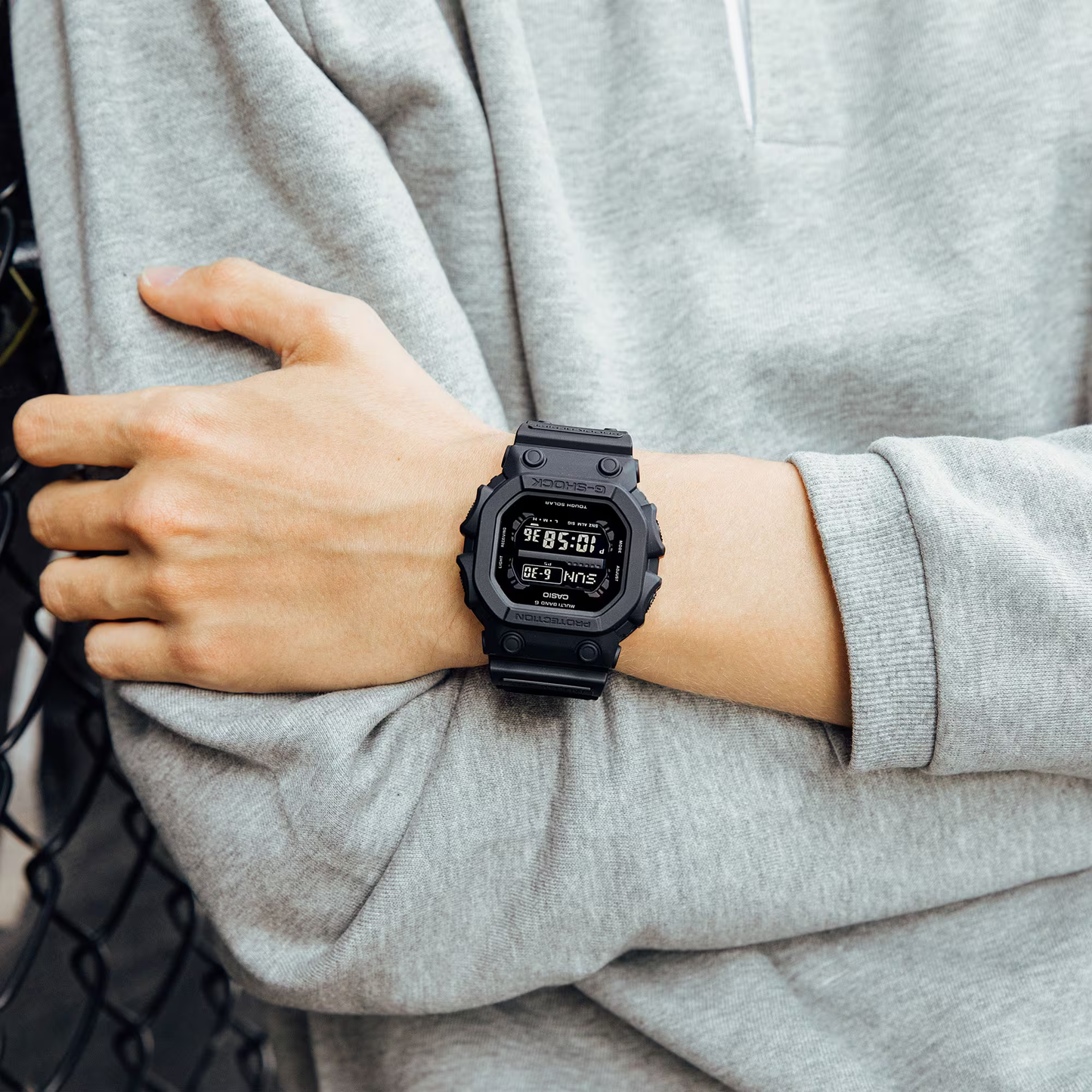 Person wearing a black digital watch on a gray background