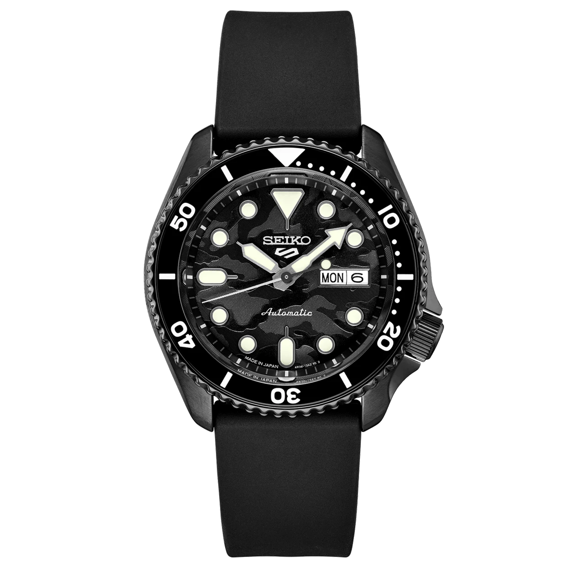 A SEIKO 5 SPORTS SRPJ39 watch with a black camouflage dial, black strap, and black case. The watch has a black uni-directional rotating bezel and displays the day/date calendar.