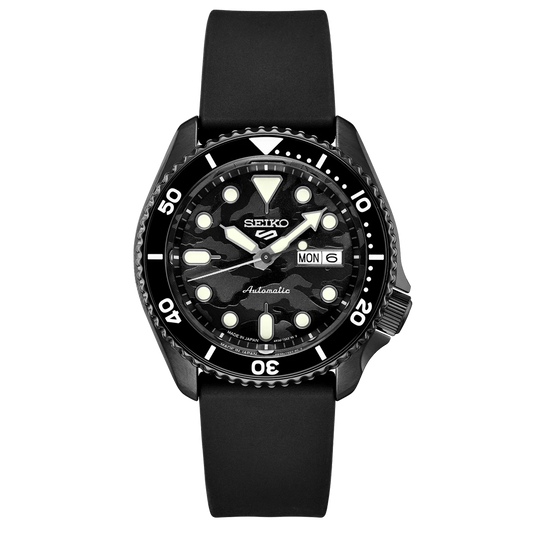 A SEIKO 5 SPORTS SRPJ39 watch with a black camouflage dial, black strap, and black case. The watch has a black uni-directional rotating bezel and displays the day/date calendar.