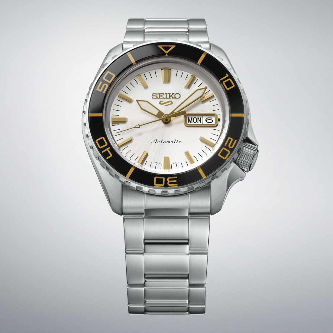SEIKO 5 Sports HDB004 front view with white dial, black and gold bezel, automatic movement text, day-date display, and stainless steel bracelet.