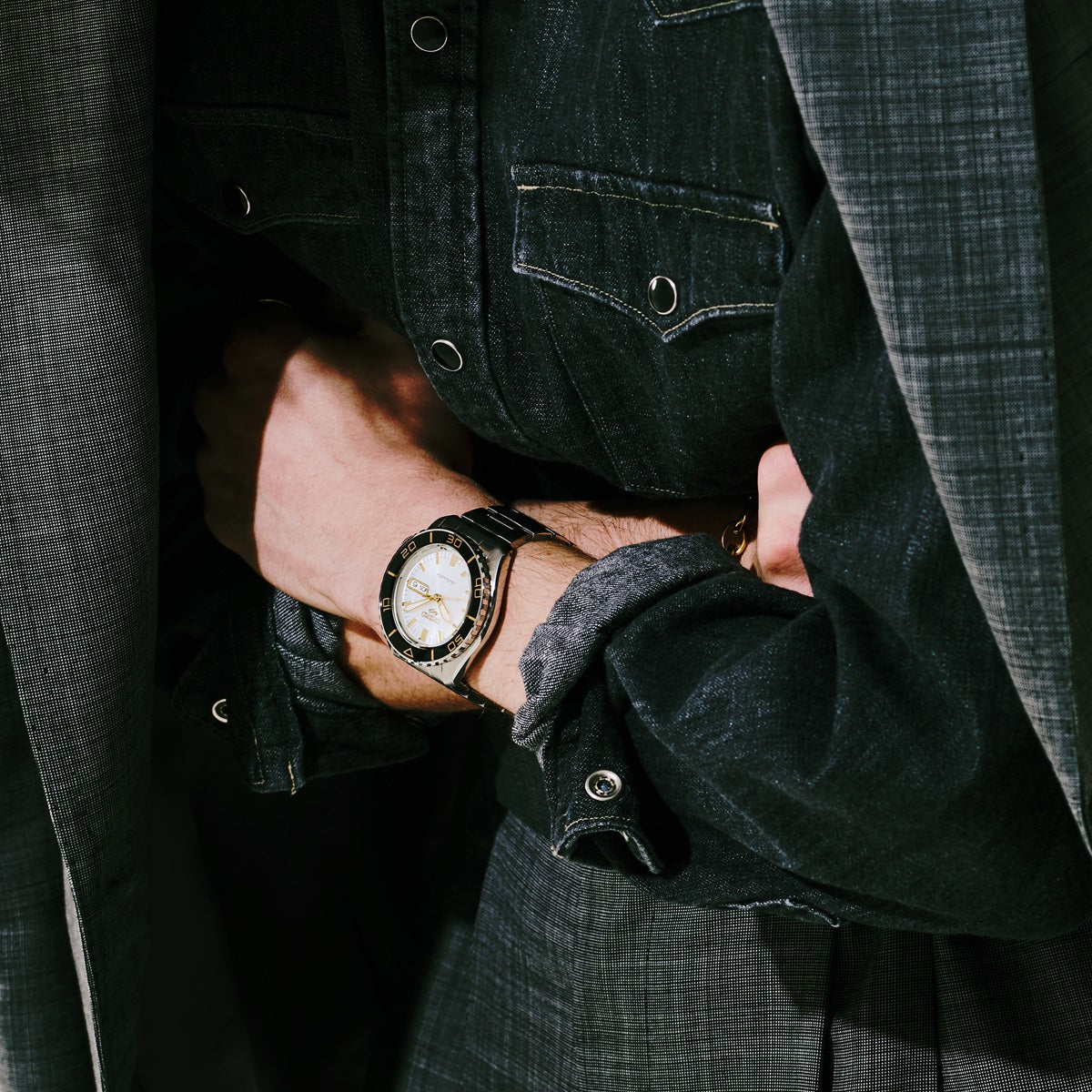 SEIKO 5 Sports HDB004 automatic watch worn on the wrist, featuring a white dial, black bezel, gold accents, and stainless steel bracelet.