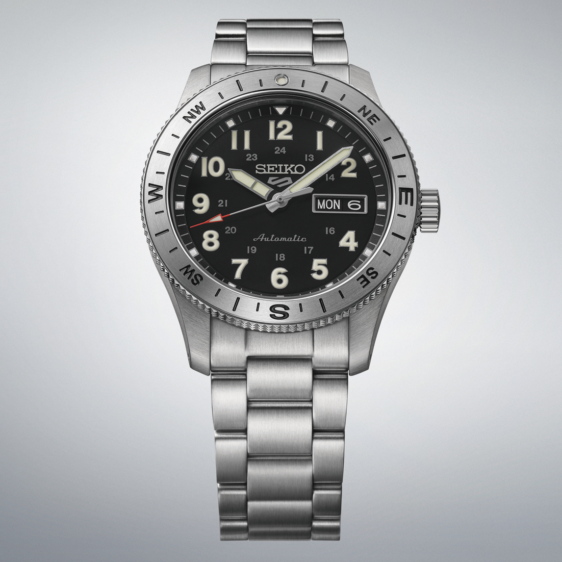 Seiko watch with black dial and silver metal bracelet on a light gray background