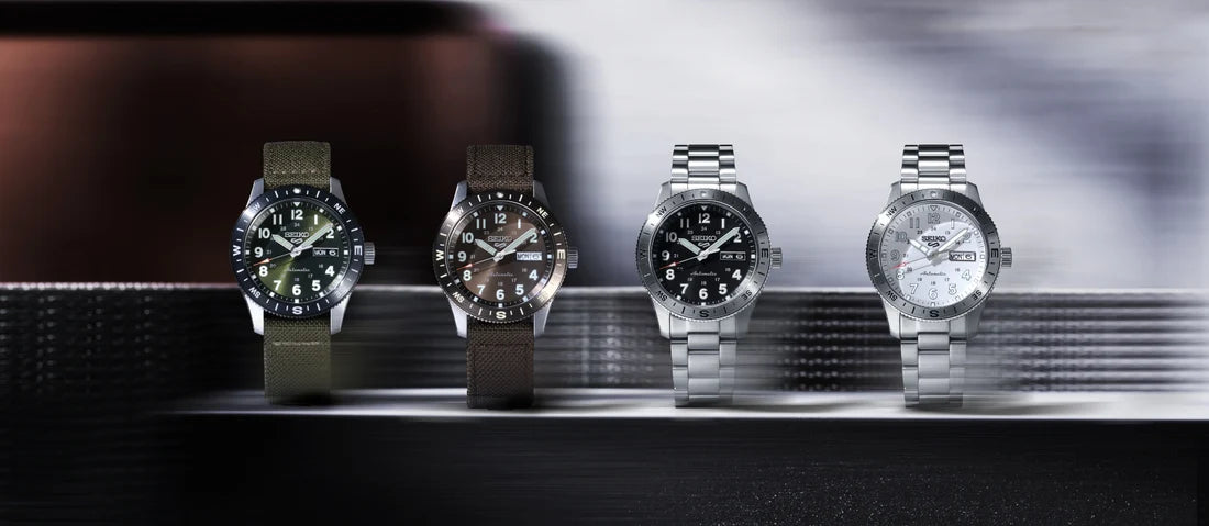 Four watches displayed on a metallic surface with a blurred background