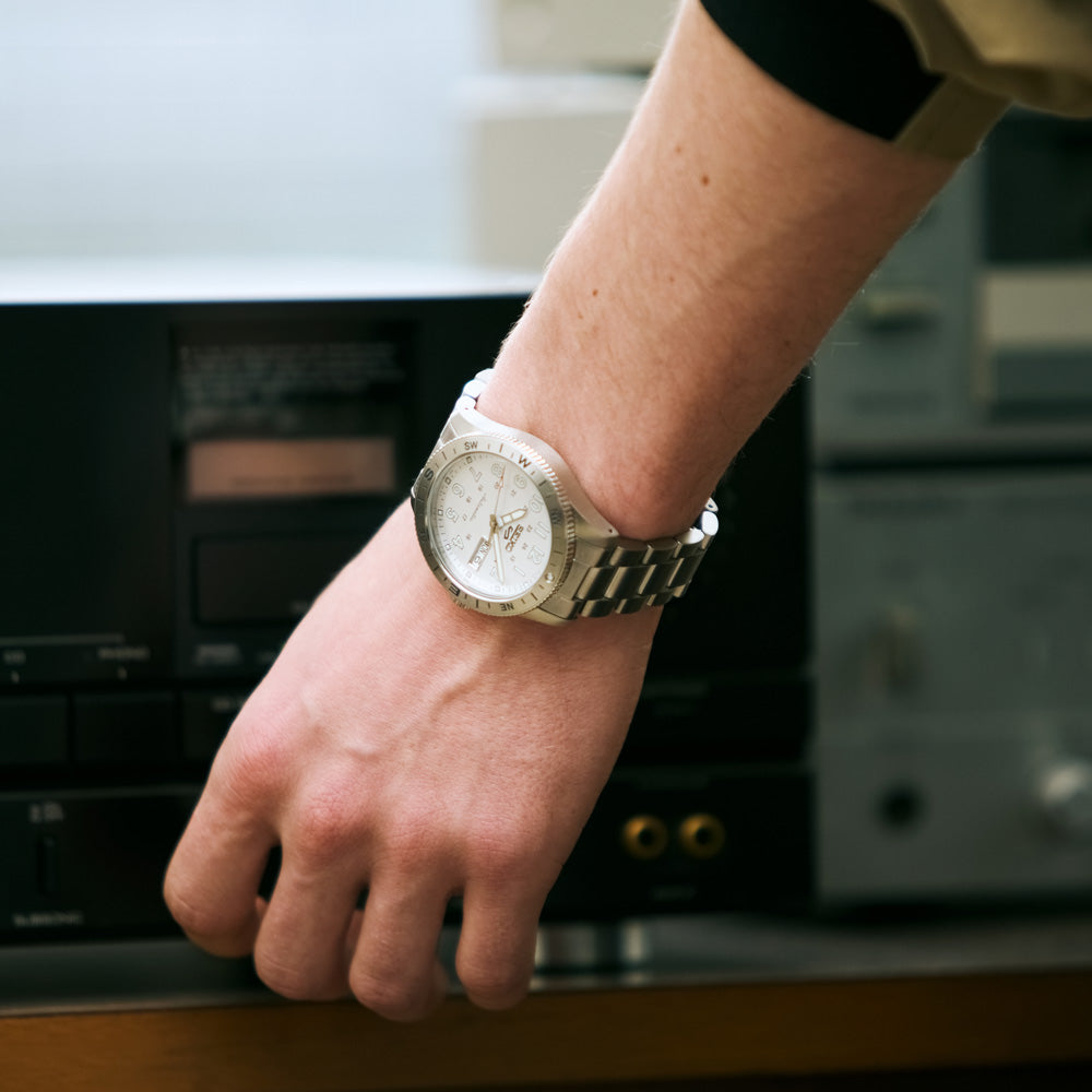 Hand wearing a gold watch with a blurred background