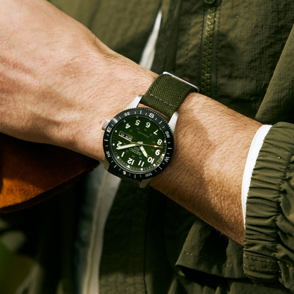 Person wearing a green watch with a matching jacket outdoors