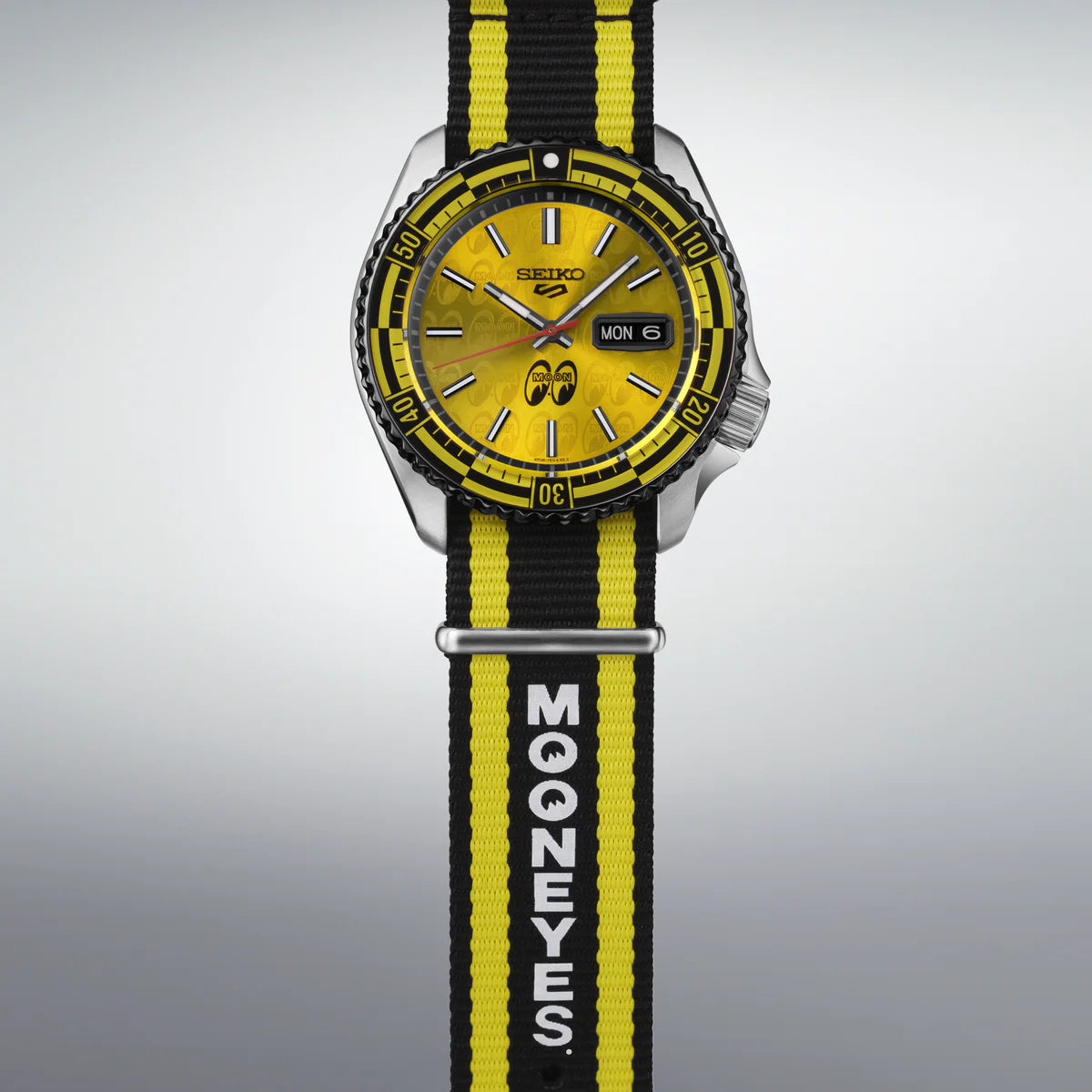 Wristwatch with yellow and black strap featuring 'Mooneyes' branding on a gray background