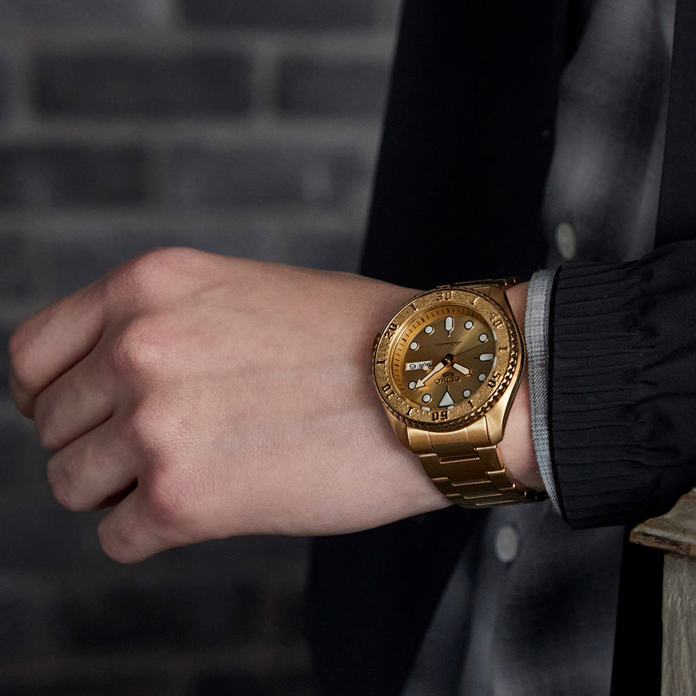 Gold wristwatch on a person's wrist with a blurred background