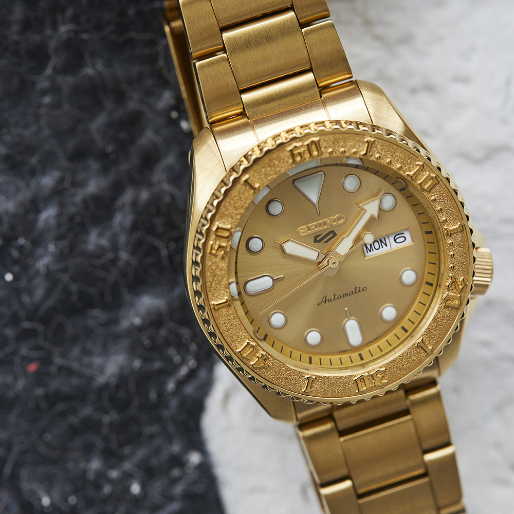 Gold wristwatch with detailed face on a textured surface