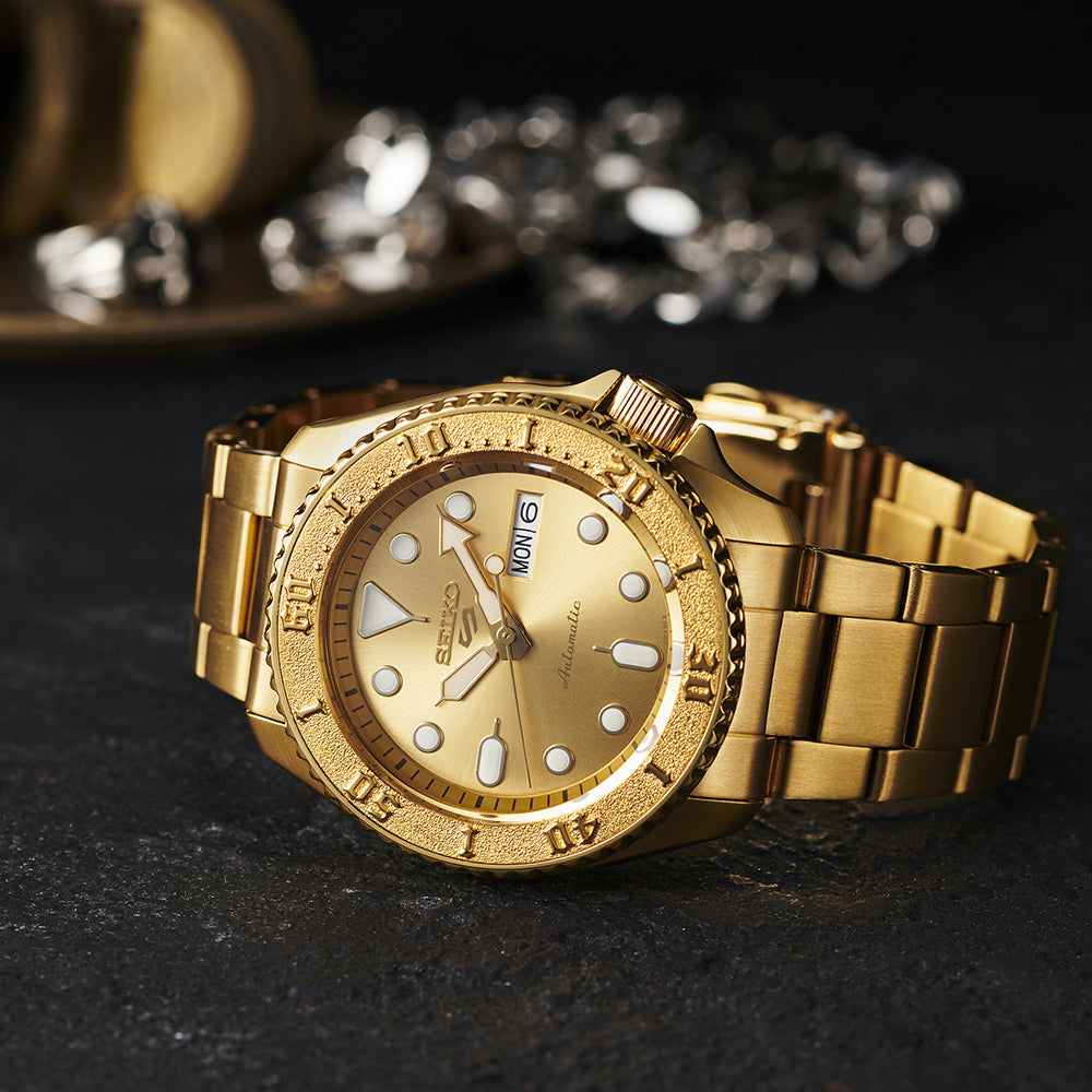 Gold wristwatch with detailed design on a dark surface