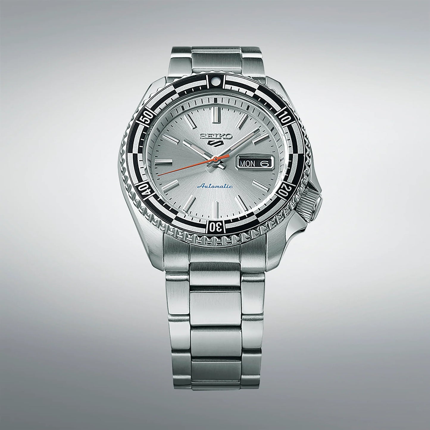 Seiko 5 Sports 55th Anniversary Special Edition automatic men's watch with silver dial, black and silver checkered rotating bezel, red-orange second hand, and stainless steel bracelet, inspired by the 1960s Seiko 5126-8130 model, available at Miseki Jewelry